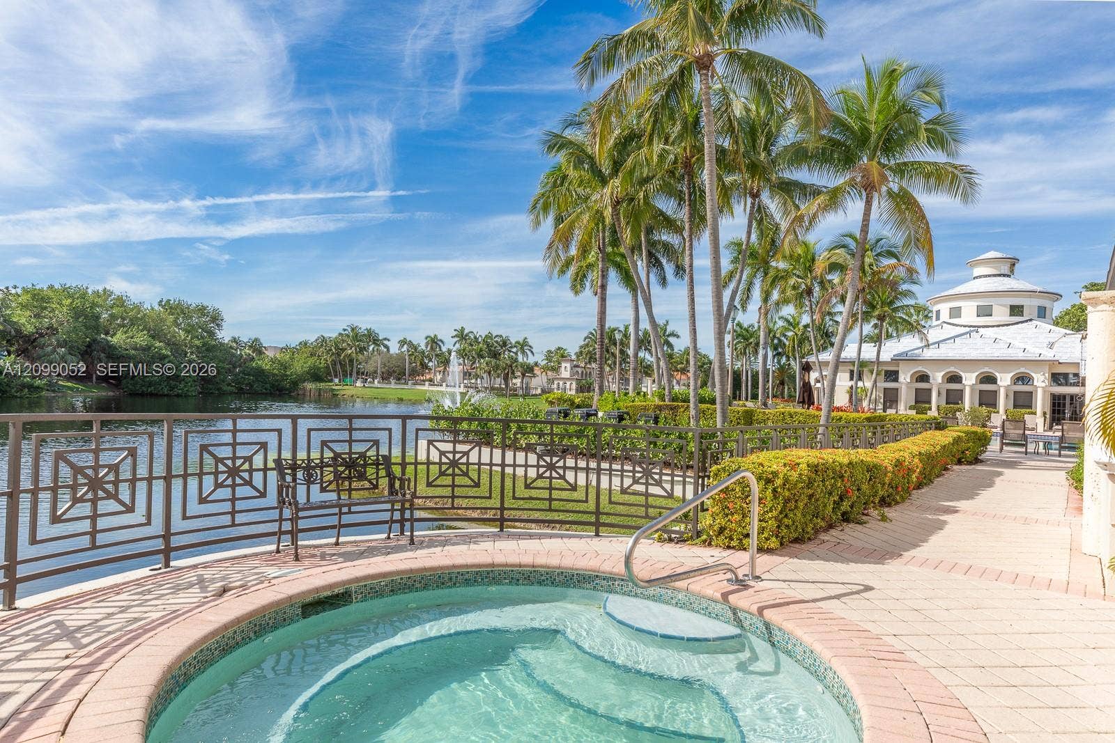 1516 Breakwater Terrace, Hollywood, FL 33019 In-ground spa with stone-tiled interior, paver patio, decorative metal perimeter fencing, and mature palm trees