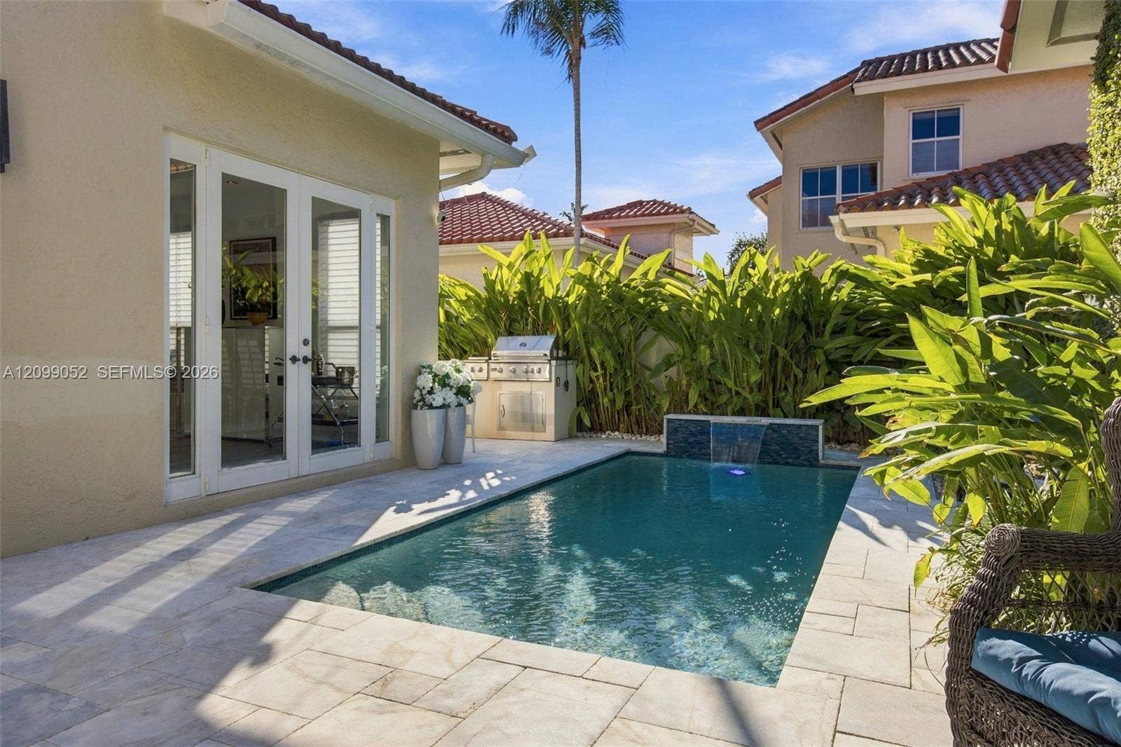 1516 Breakwater Terrace, Hollywood, FL 33019 Backyard featuring an in-ground swimming pool with a tiled water feature, stone-paver decking, and a built-in outdoor grill station