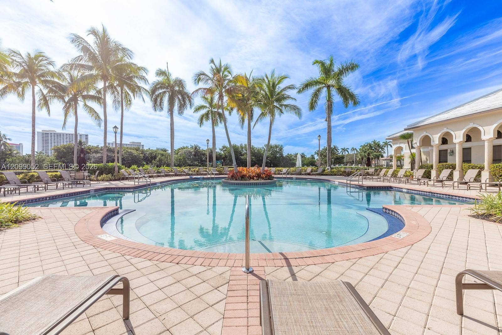 1516 Breakwater Terrace, Hollywood, FL 33019 In-ground swimming pool featuring a curved perimeter, stepped entry, central garden island, and surrounding paver patio with a colonnade structure