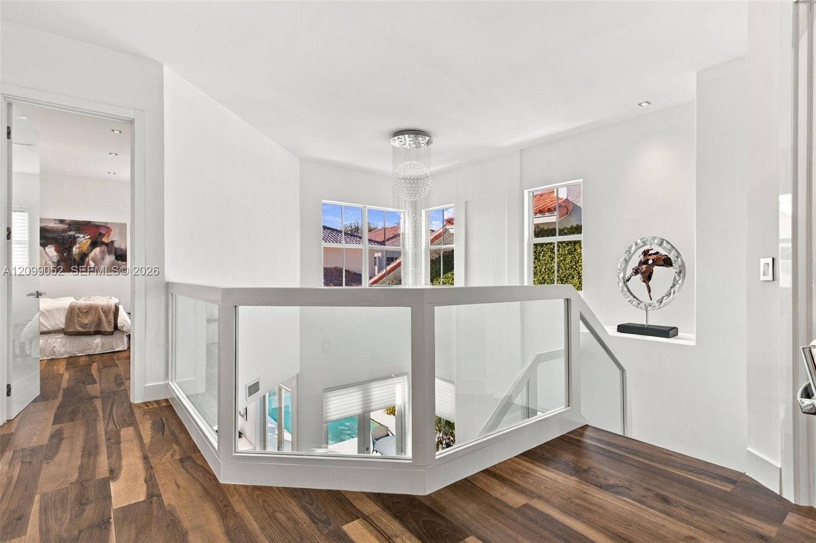 1516 Breakwater Terrace, Hollywood, FL 33019 Landing featuring wood-finish flooring, glass panel railing, recessed ceiling lighting, and a tiered crystal chandelier