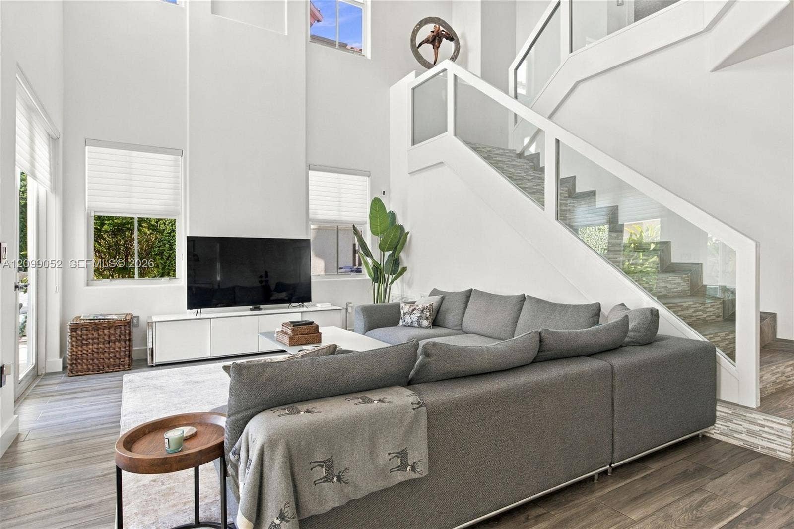 1516 Breakwater Terrace, Hollywood, FL 33019 Double-height ceiling, glass-paneled staircase railing, wood-finish flooring, and expansive windows