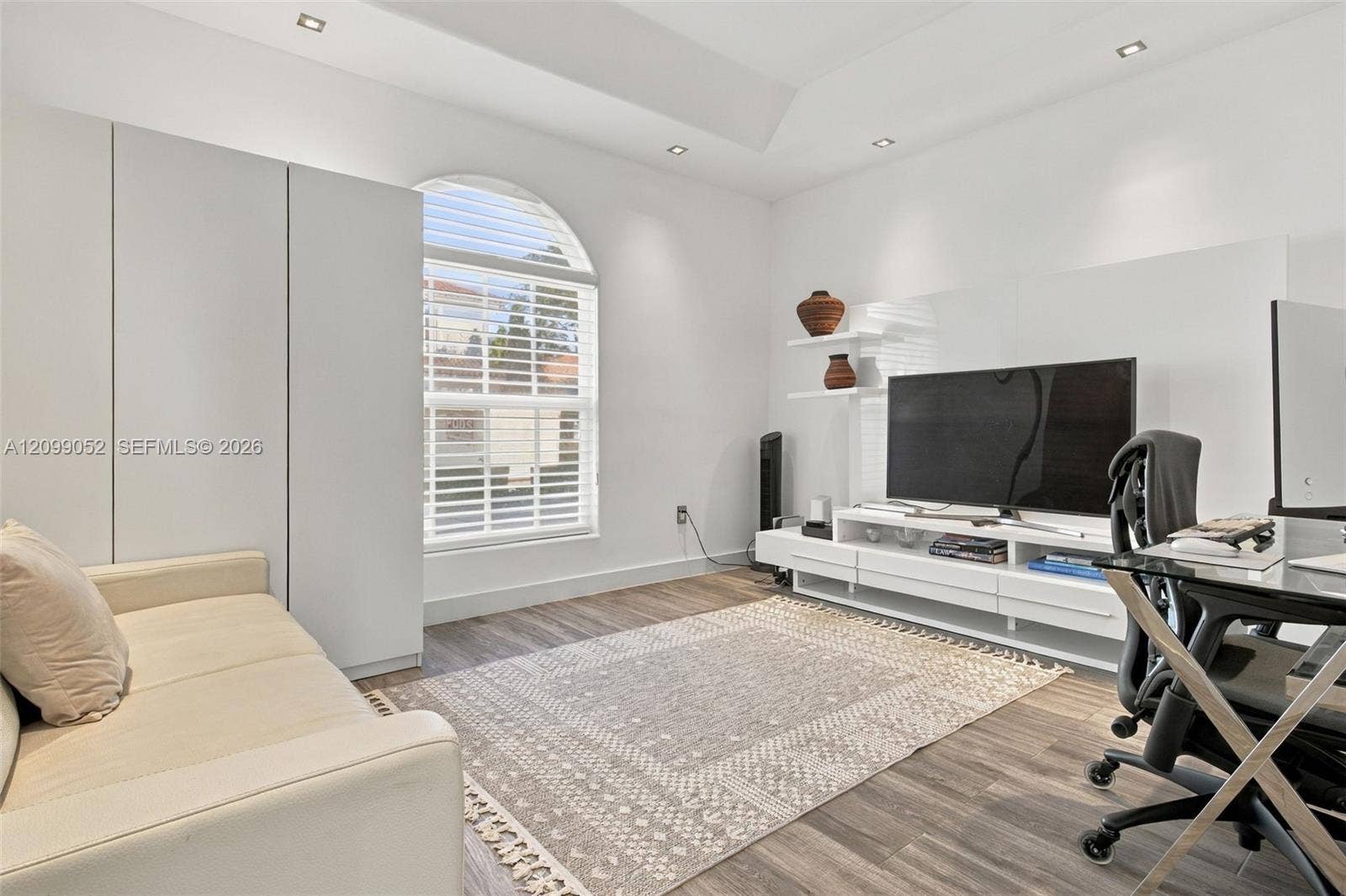 1516 Breakwater Terrace, Hollywood, FL 33019 Tray ceiling with recessed lighting, arched window with horizontal blinds, built-in floor-to-ceiling cabinetry, and wood-finish flooring