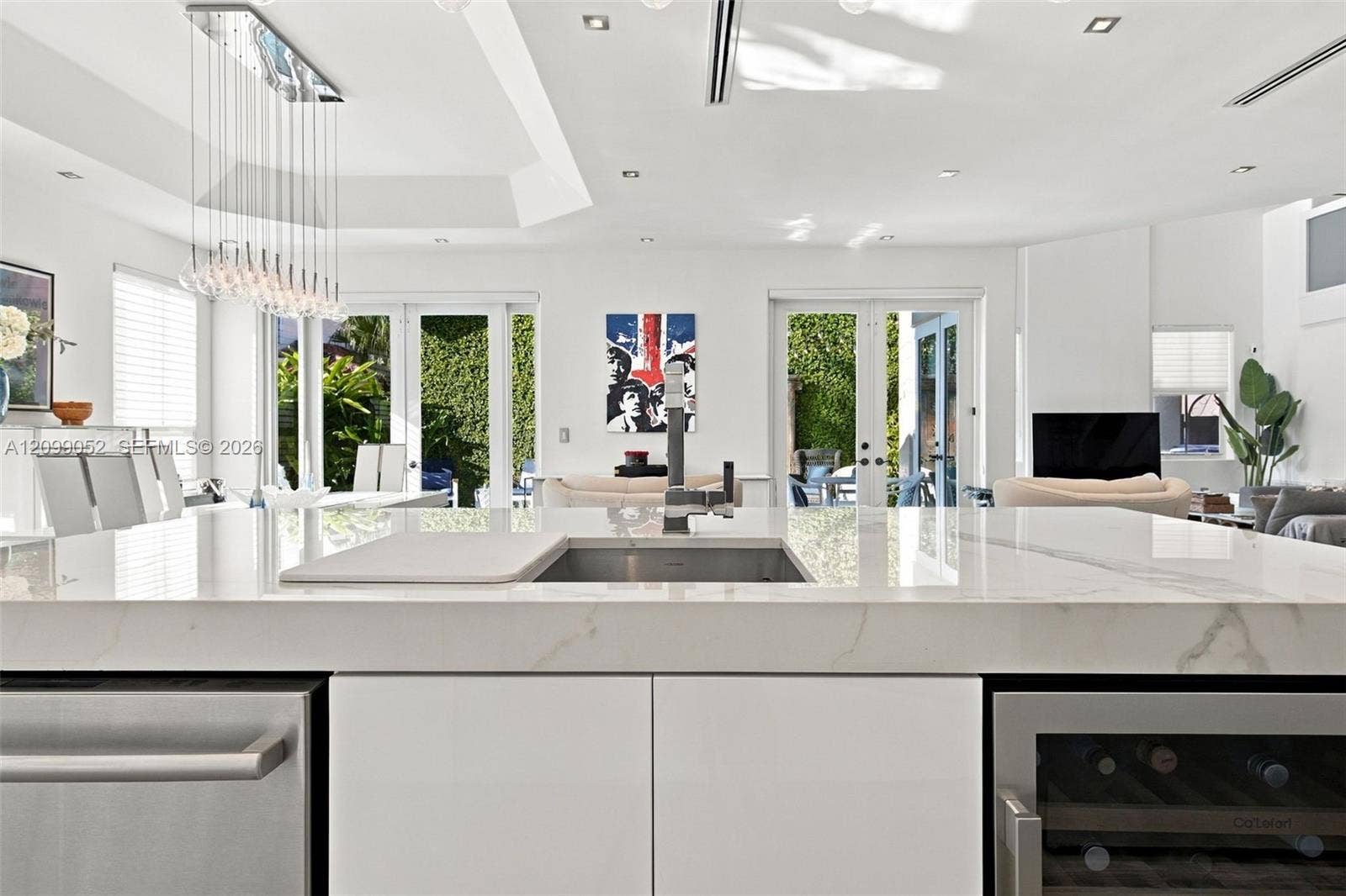 1516 Breakwater Terrace, Hollywood, FL 33019 Kitchen island featuring a stone-look countertop, undermount sink with a high-arch faucet, built-in stainless steel dishwasher, integrated wine refrigerator, and minimalist flat-panel cabinetry