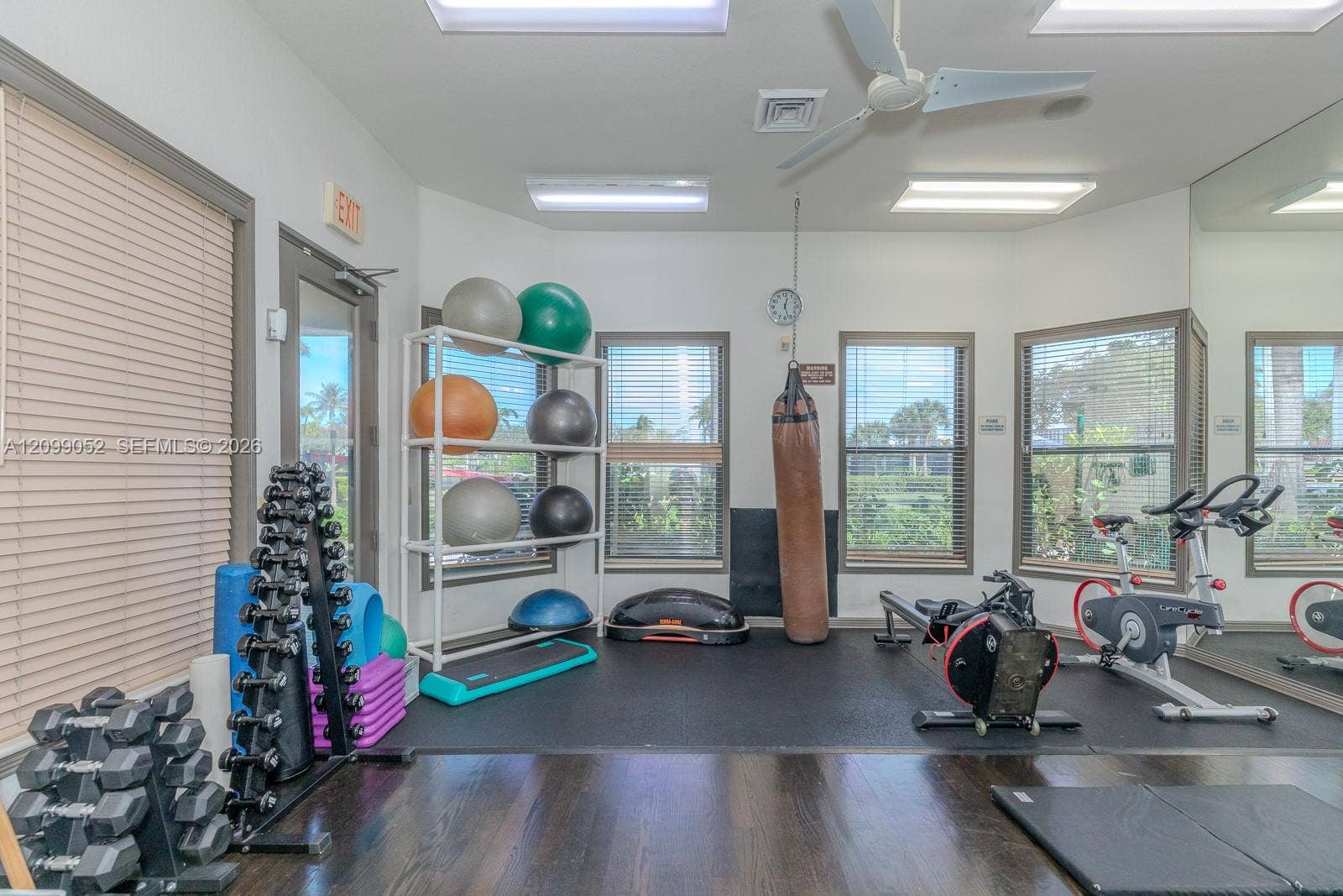 1516 Breakwater Terrace, Hollywood, FL 33019 Dedicated fitness area featuring dark wood-finish flooring, rubberized gym flooring, floor-to-ceiling wall mirror, recessed ceiling lighting, and multiple windows with horizontal blinds