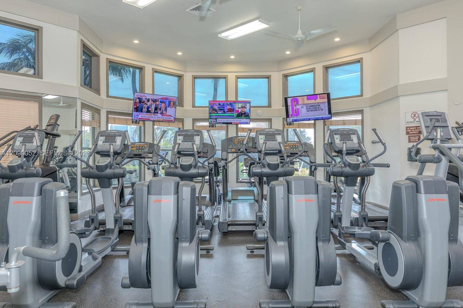1516 Breakwater Terrace, Hollywood, FL 33019 Fitness center featuring a curved wall of windows, multiple elliptical machines, treadmills, and ceiling-mounted televisions