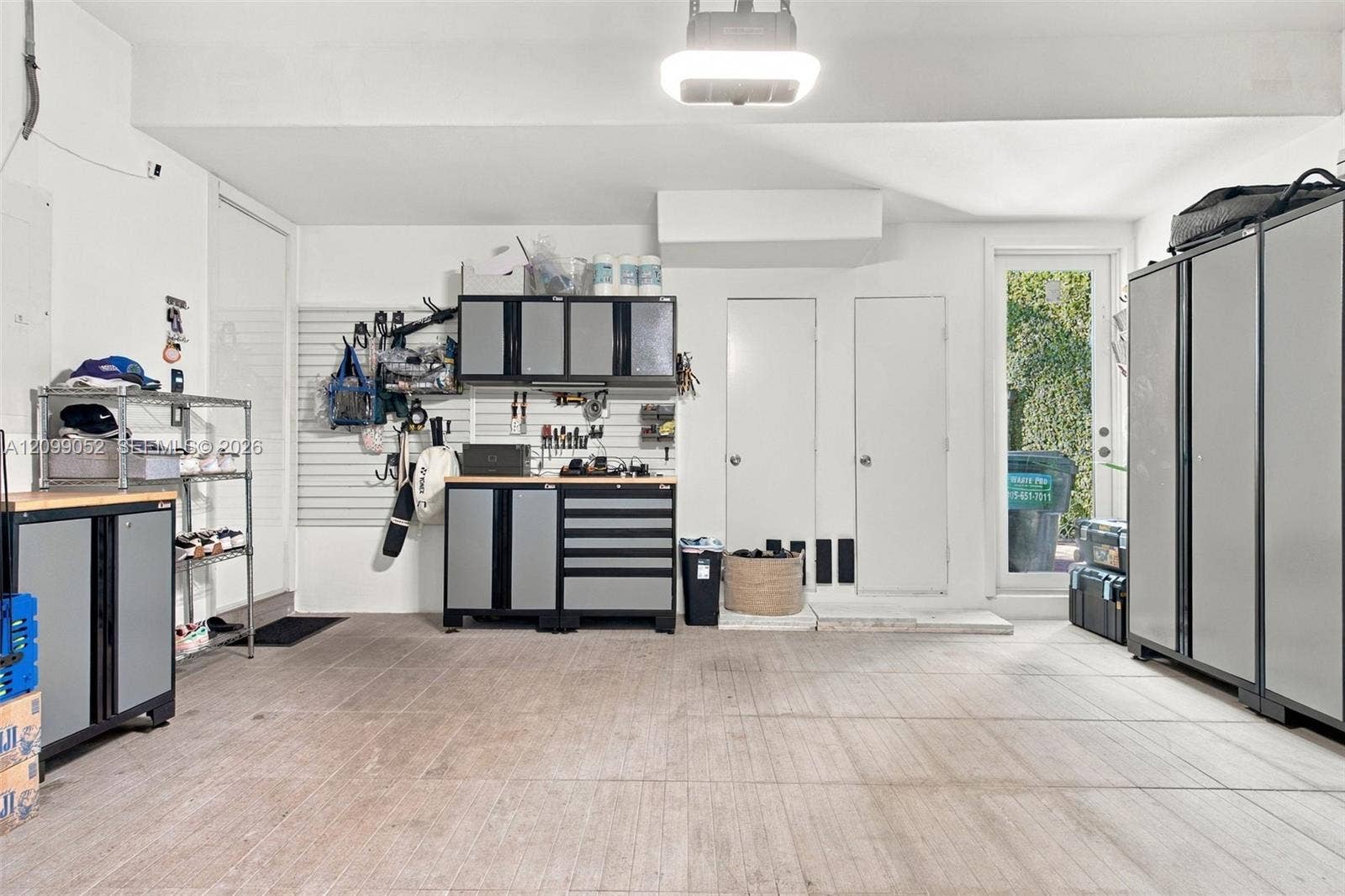 1516 Breakwater Terrace, Hollywood, FL 33019 Finished garage featuring integrated wall-mounted storage panels, custom built-in cabinetry with metal-finish doors, durable concrete flooring, and a glass-paneled exterior door