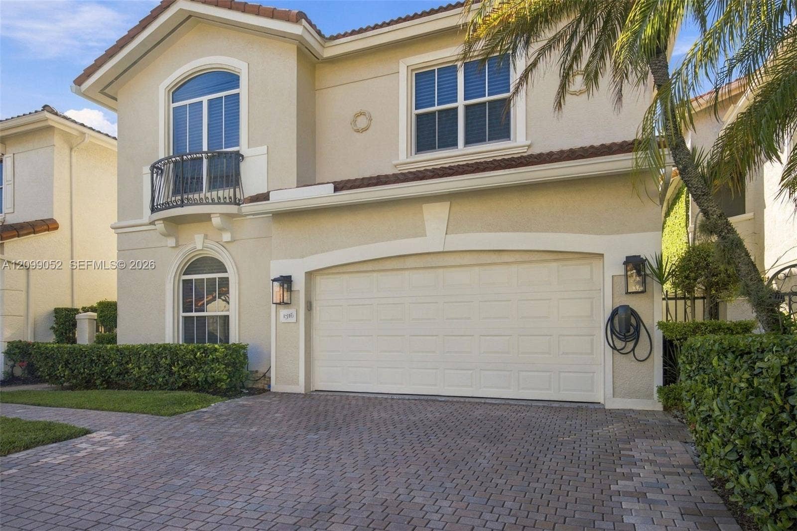 1516 Breakwater Terrace, Hollywood, FL 33019 Stucco exterior featuring a paver driveway, arched windows, decorative metal balcony, and tile roofing