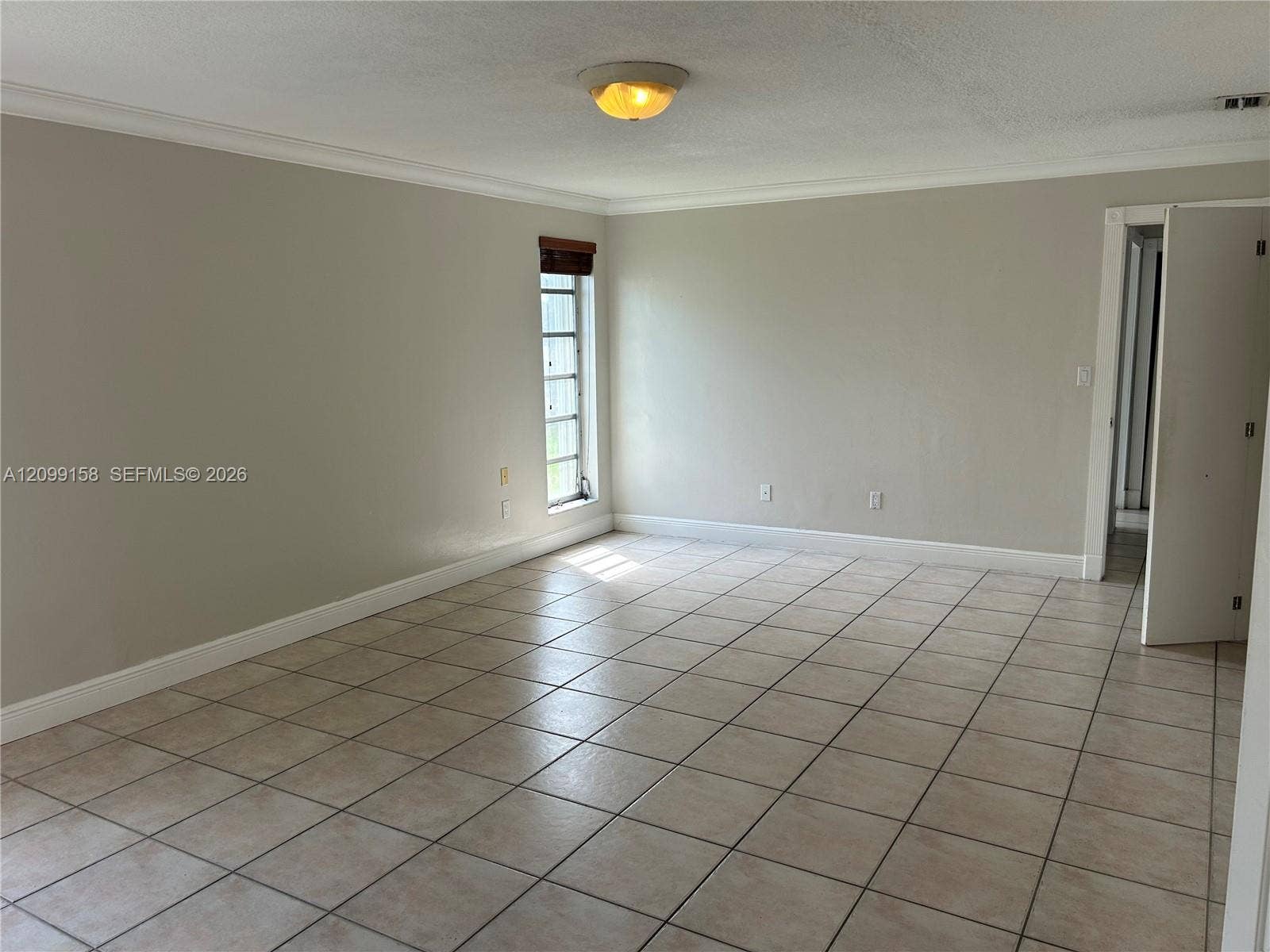 1490 Lenape Drive, Miami Springs, FL 33166 Room featuring neutral-toned ceramic tile flooring, crown molding, and two multi-pane windows with horizontal wood-finish blinds