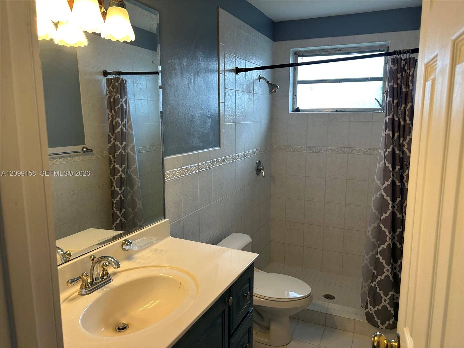 1490 Lenape Drive, Miami Springs, FL 33166 Spacious interior featuring large-format tile flooring, crown molding, multi-pane windows, and a decorative wrought iron chandelier