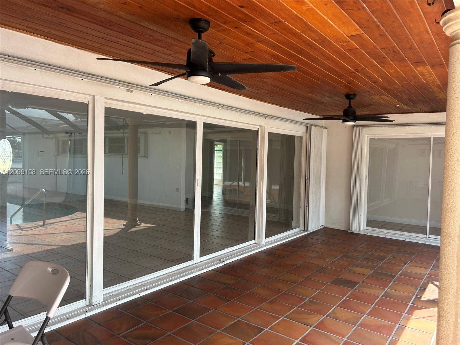 1490 Lenape Drive, Miami Springs, FL 33166 Screened-in pool area featuring terracotta-style tile decking, a metal-framed enclosure, and integrated handrails