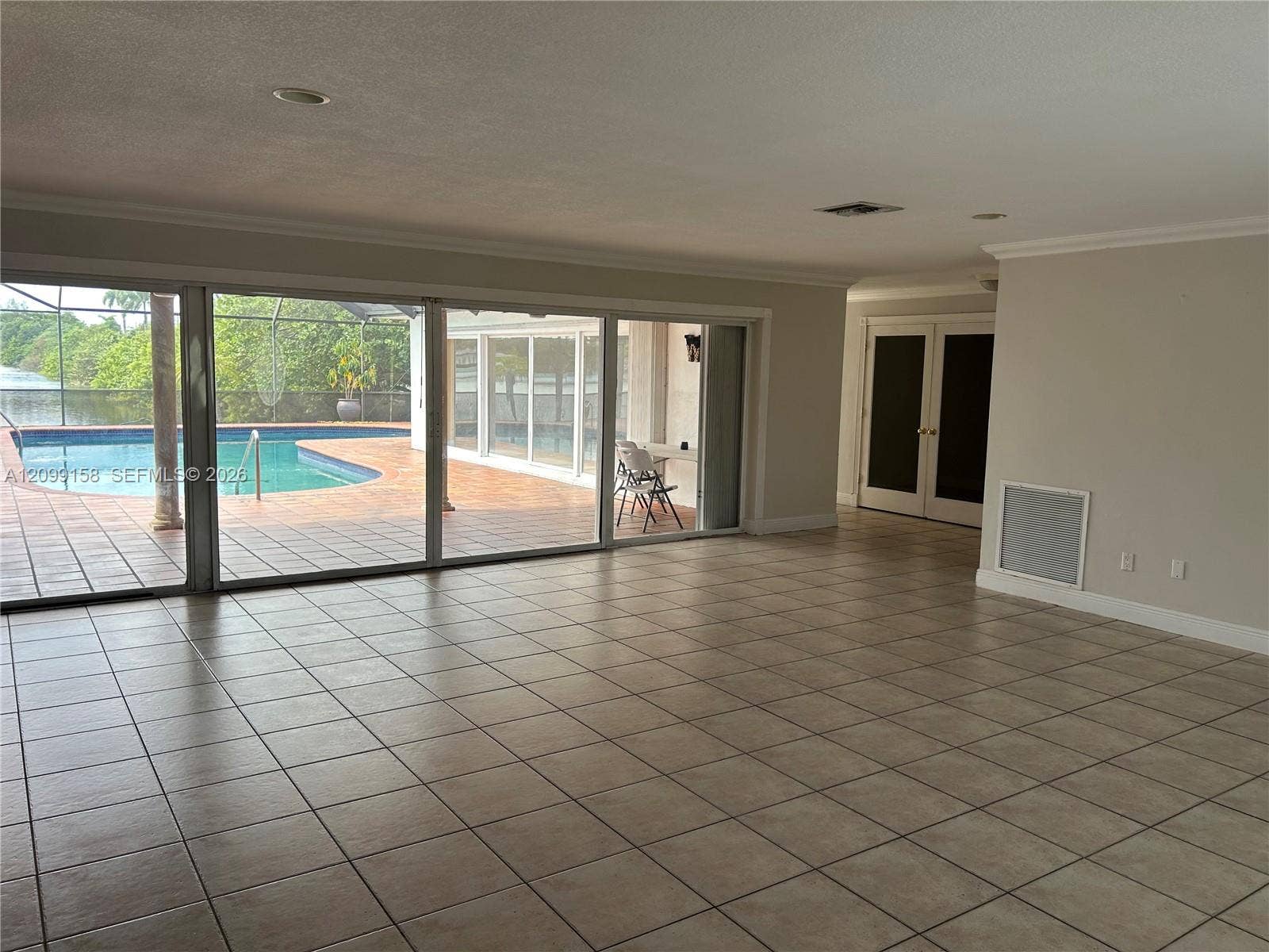 1490 Lenape Drive, Miami Springs, FL 33166 Spacious open-concept living area with tile flooring throughout, recessed ceiling lighting, and multiple glass doors with sidelights providing natural illumination