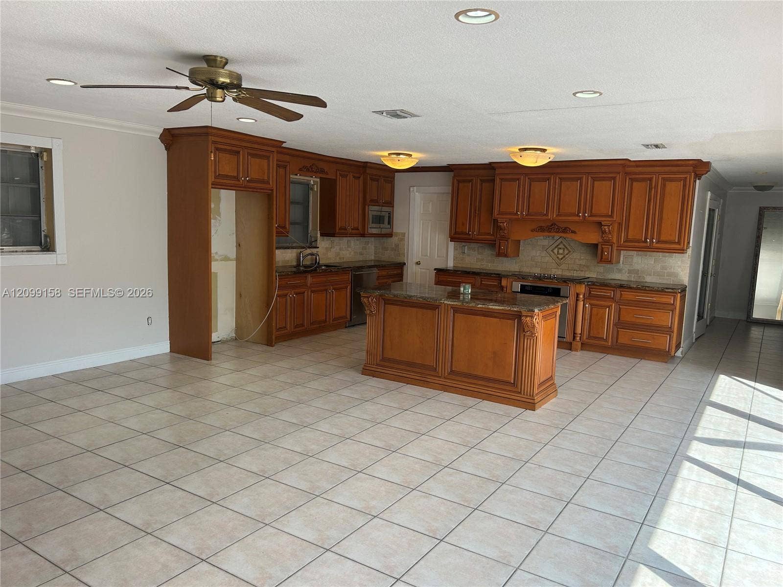 1490 Lenape Drive, Miami Springs, FL 33166 Kitchen featuring custom wood cabinetry, central island, stone-surface countertops, tile flooring, and multi-panel sliding glass doors