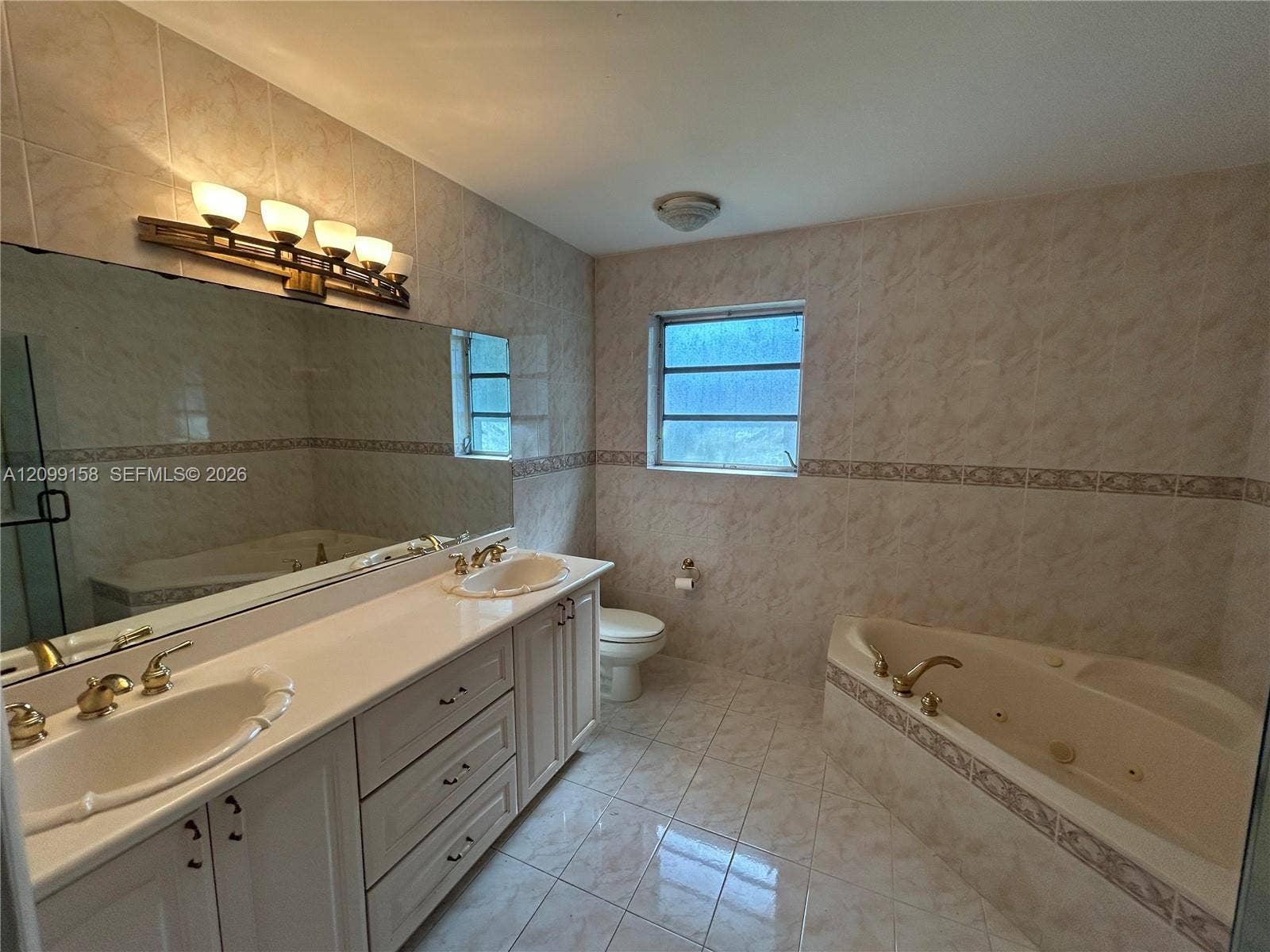 1490 Lenape Drive, Miami Springs, FL 33166 Bathroom featuring a double-sink vanity with light-toned cabinetry, an oversized wall-to-wall mirror, and a glass-enclosed shower with tiled walls