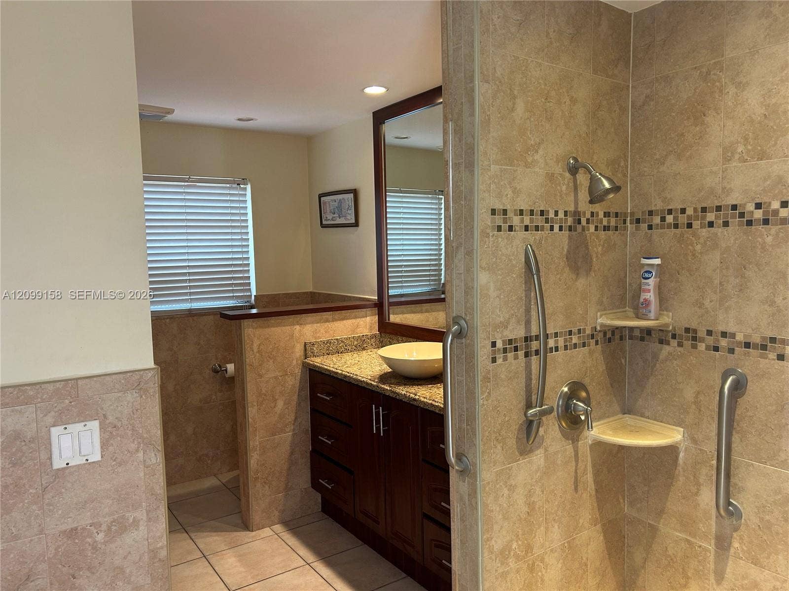 1490 Lenape Drive, Miami Springs, FL 33166 Stone-topped vanity featuring a vessel sink and single-handle faucet, tiled shower with glass enclosure, and large-format floor tiling