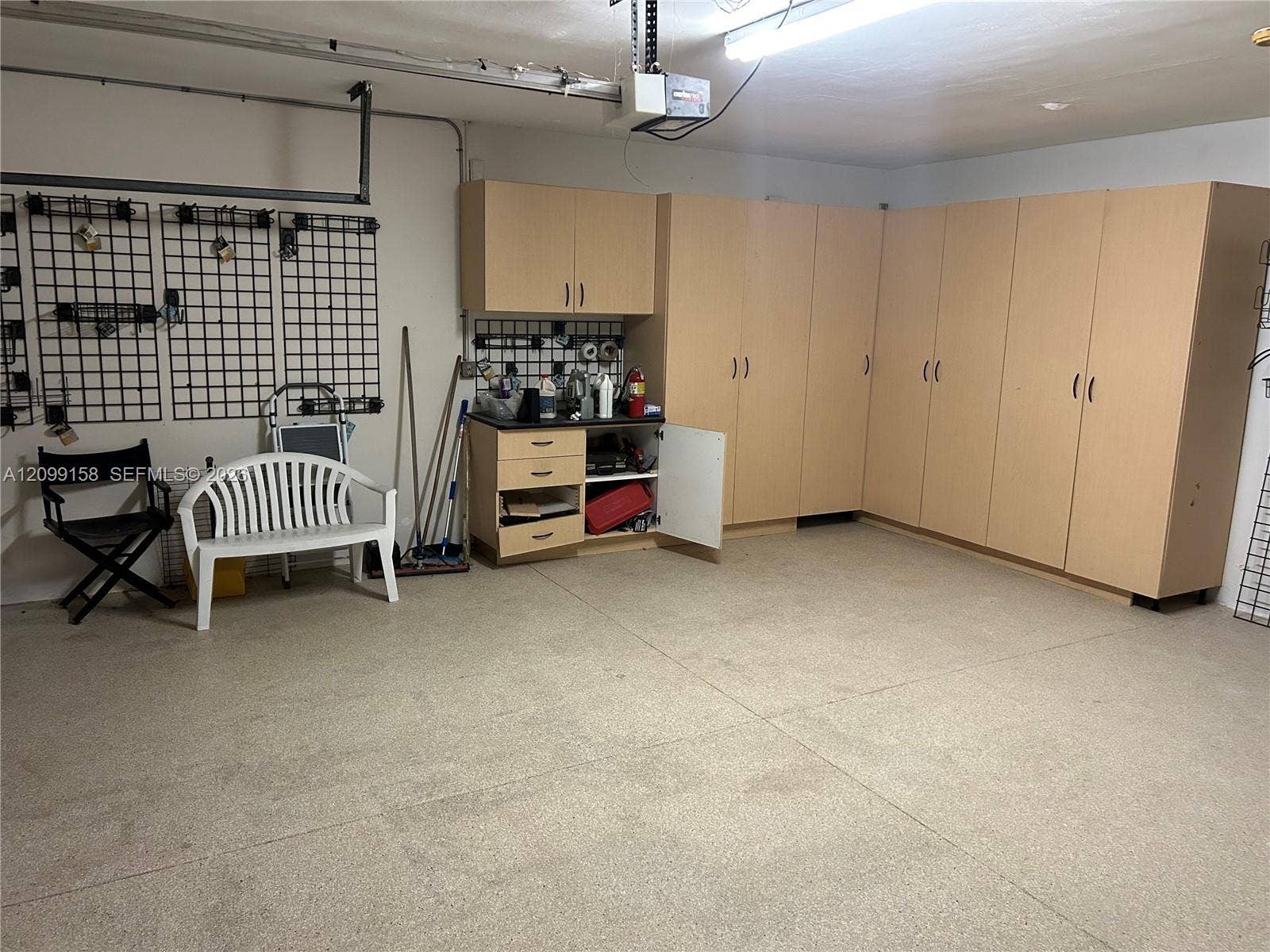 1490 Lenape Drive, Miami Springs, FL 33166 Garage featuring a sectional overhead door, epoxy-coated concrete flooring, built-in storage cabinetry, and wall-mounted organization panels