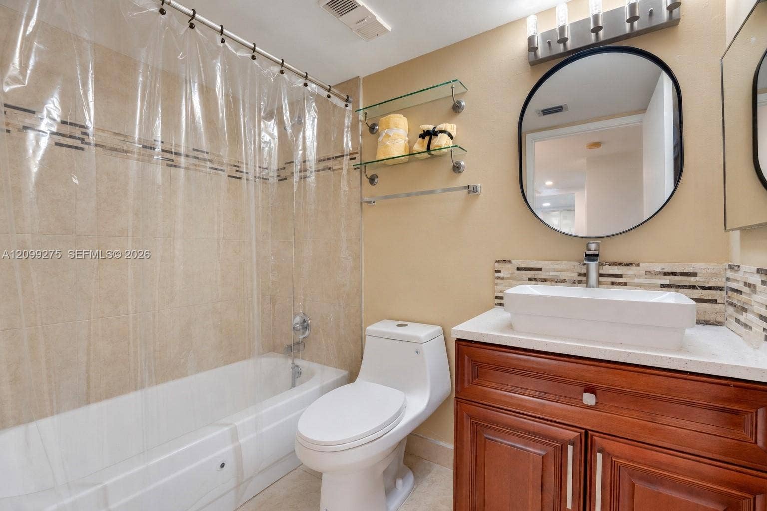 800 N Miami Avenue, #E-902, Miami, Miami, FL 33136 Well-appointed bathroom featuring a modern vessel sink, wood vanity, large round mirror, and a bathtub with tiled walls and a clear shower curtain.