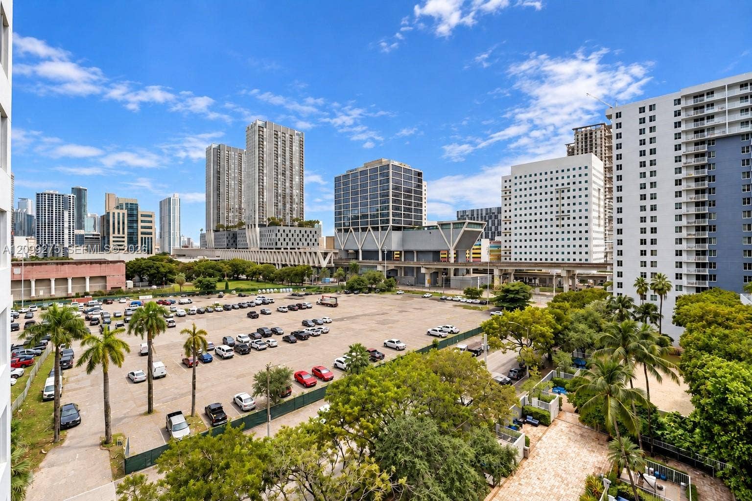 800 N Miami Avenue, #E-902, Miami, Miami, FL 33136 Panoramic city views featuring a vibrant downtown skyline, high-rise buildings, and a spacious parking area, complemented by lush tropical greenery and palm trees.