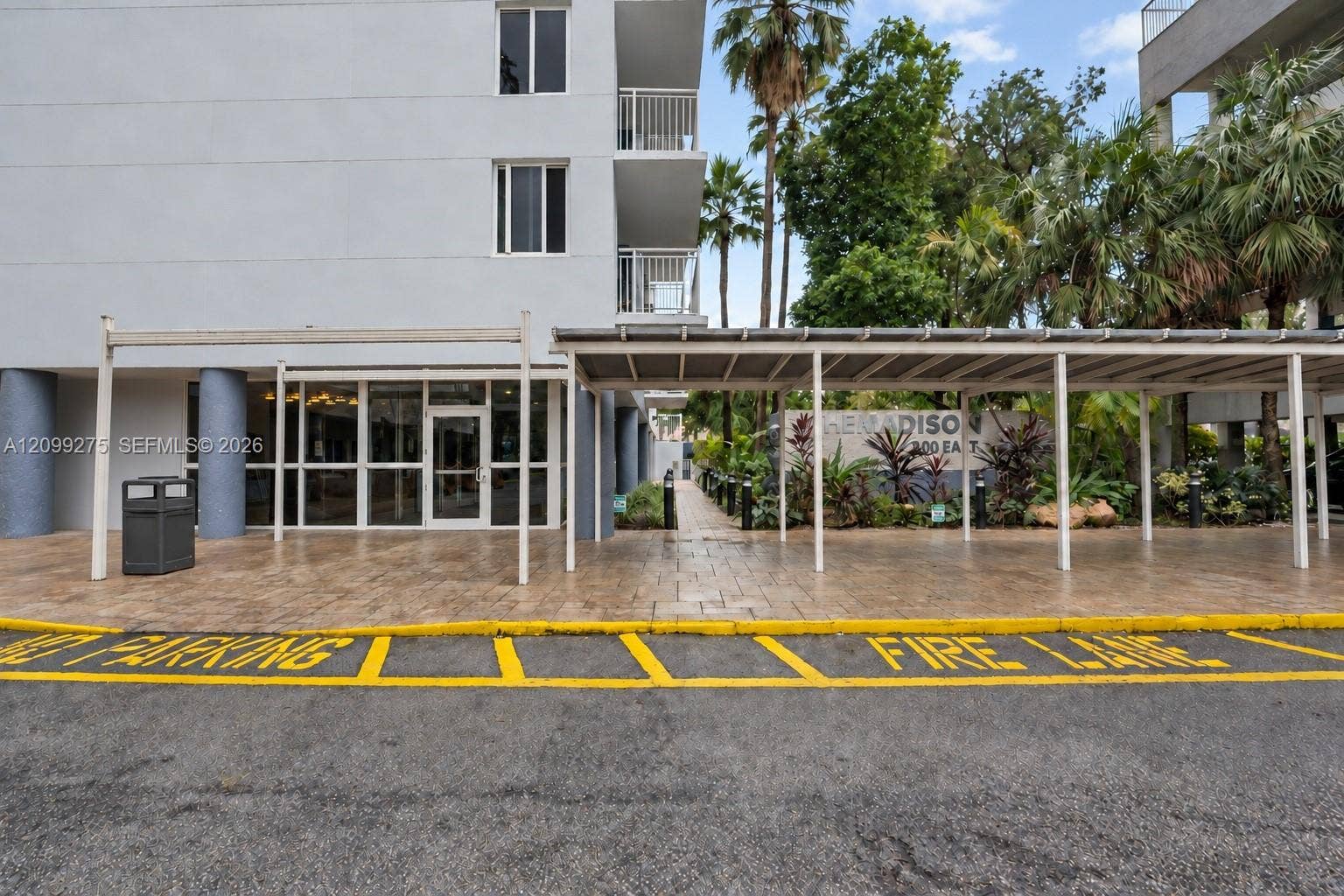 800 N Miami Avenue, #E-902, Miami, Miami, FL 33136 Welcoming building entrance with covered drop-off access, glass entry doors, and lush tropical landscaping surrounding The Madison.