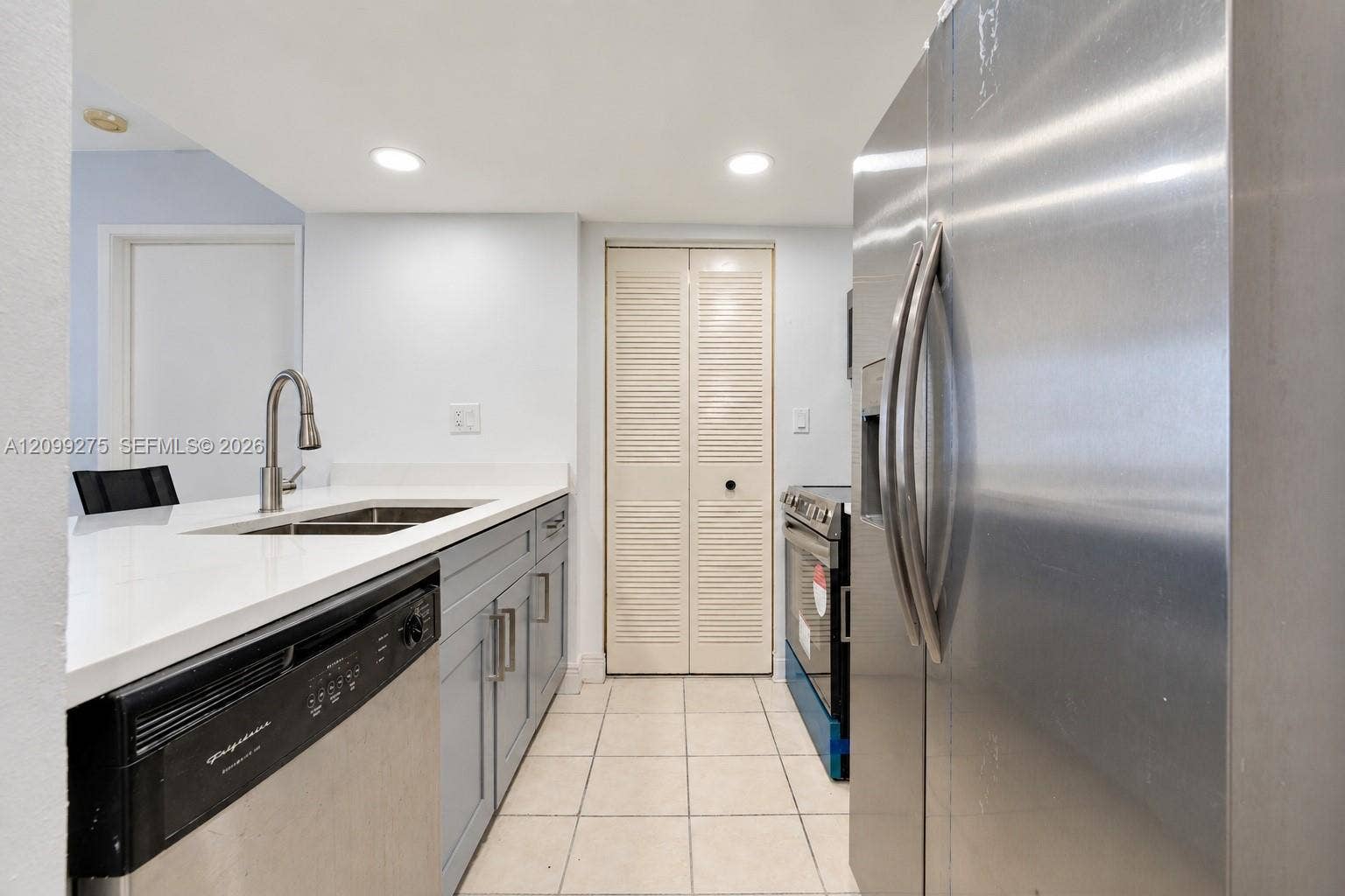 800 N Miami Avenue, #E-902, Miami, Miami, FL 33136 Bright kitchen and entryway featuring a breakfast bar with two stools, white countertops, stainless steel appliances, recessed lighting, and tiled flooring.