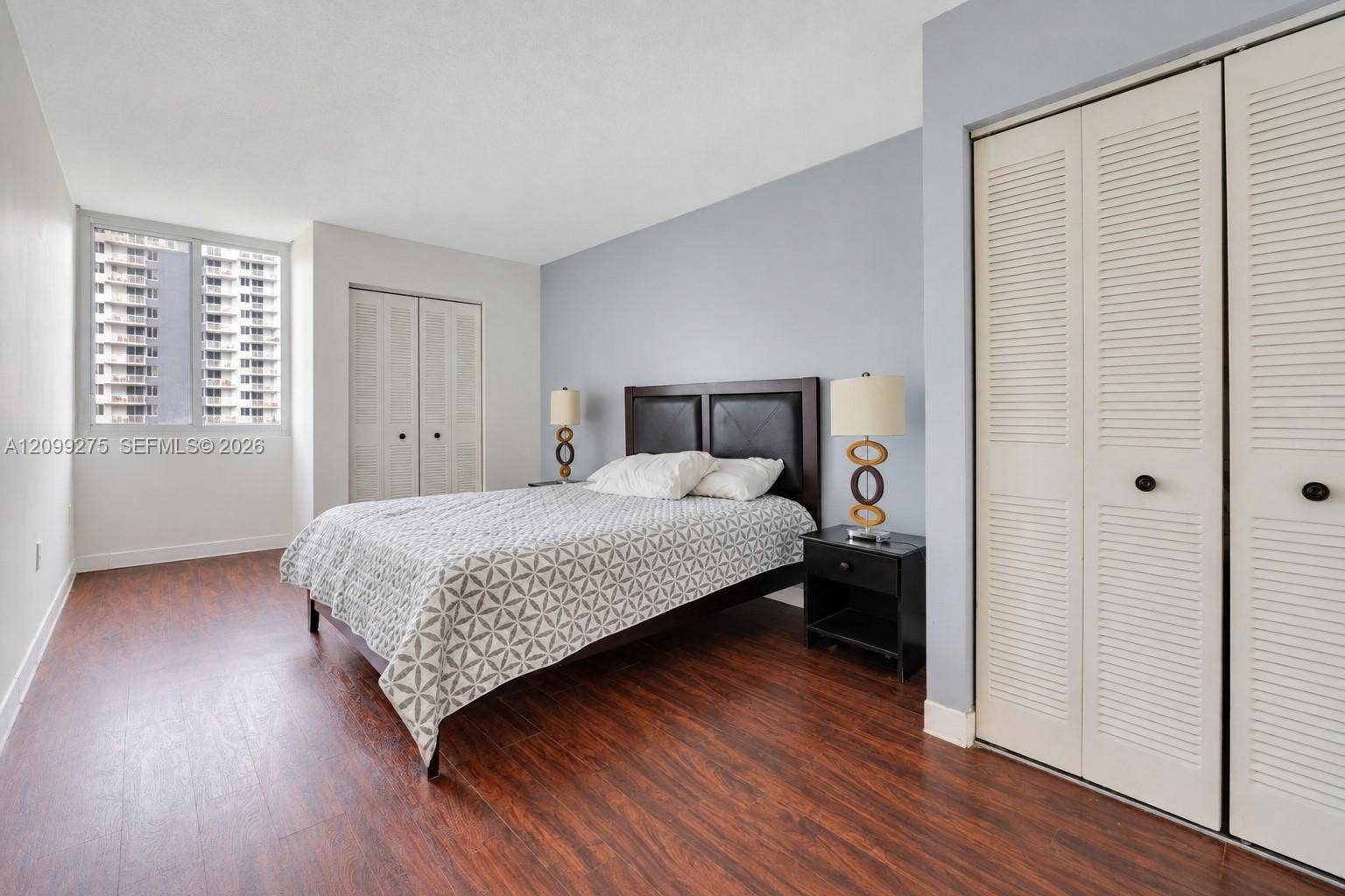 800 N Miami Avenue, #E-902, Miami, Miami, FL 33136 Spacious bedroom featuring elegant wood flooring, a sophisticated upholstered headboard, and ample closet space, creating a refined and inviting retreat.