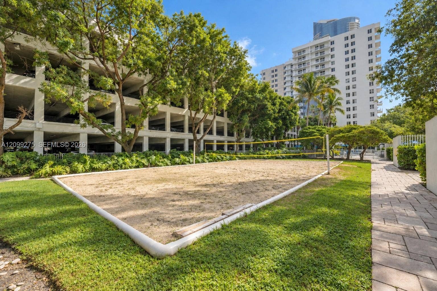 800 N Miami Avenue, #E-902, Miami, Miami, FL 33136 Outdoor sand volleyball court surrounded by lush tropical landscaping, mature shade trees, and residential high-rises, offering residents a relaxing space for recreation and outdoor activities.