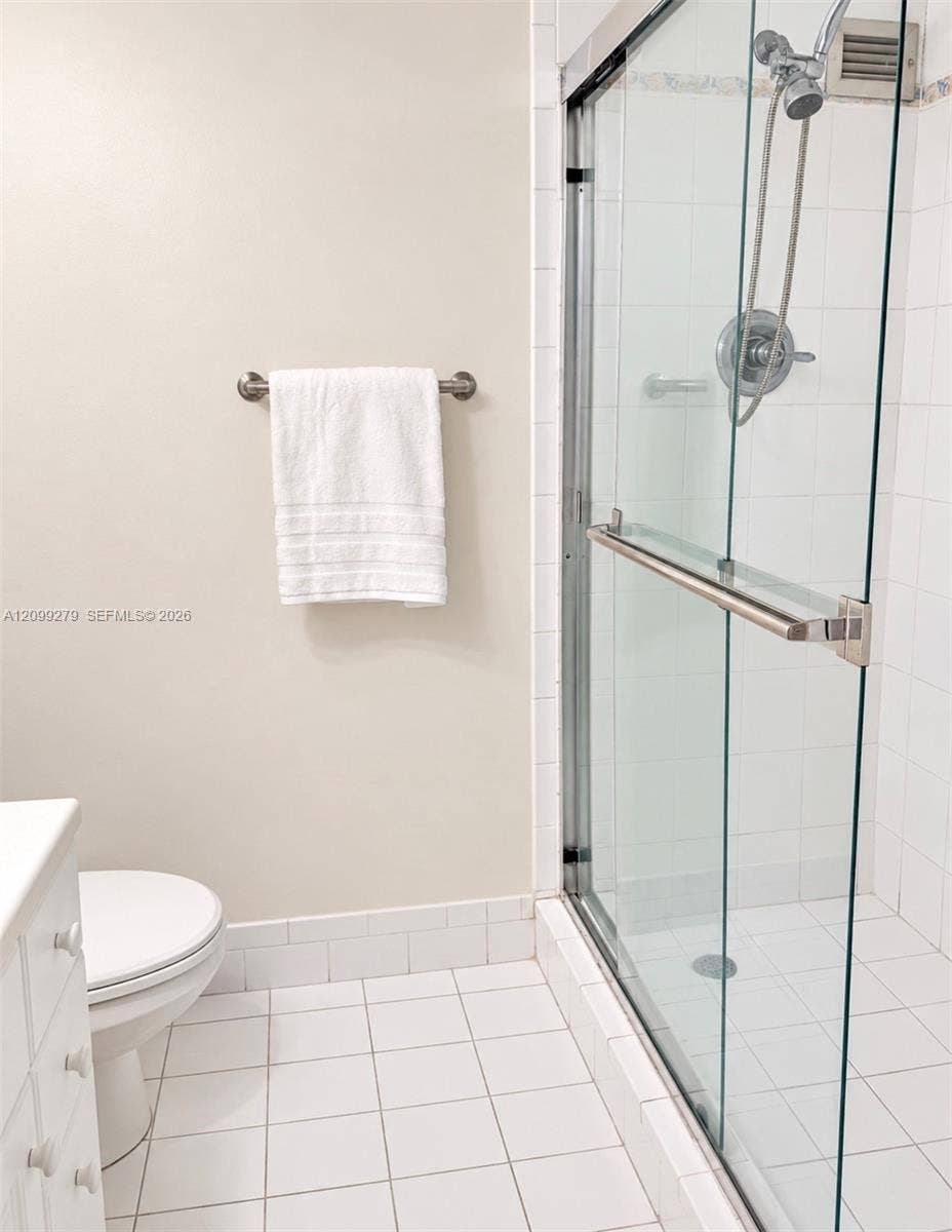 5151 Collins Avenue, #921, Miami Beach, Miami Beach, FL 33140 Walk-in shower featuring a frameless glass enclosure, polished metal hardware, and a handheld showerhead, finished with white tile wall and floor surfaces