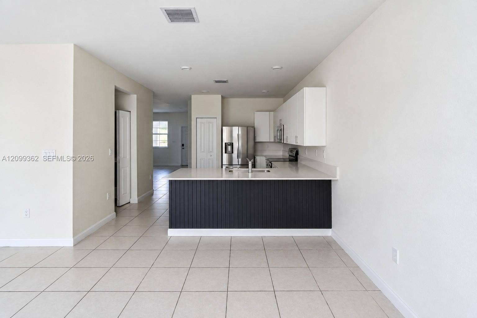 16230 SW 290th Terrace, Homestead, FL 33033 Kitchen featuring white cabinetry, a peninsula with vertical slat detailing, light-toned countertops, tile flooring, and stainless steel appliances