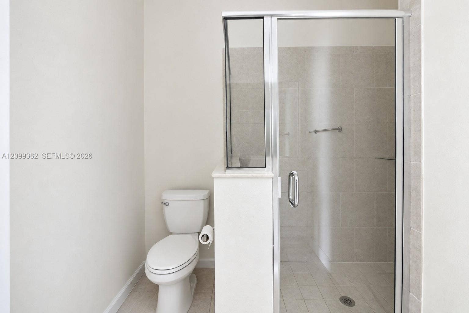 16230 SW 290th Terrace, Homestead, FL 33033 Walk-in shower with a glass enclosure, neutral tile surround, and chrome hardware, paired with a standard-profile toilet