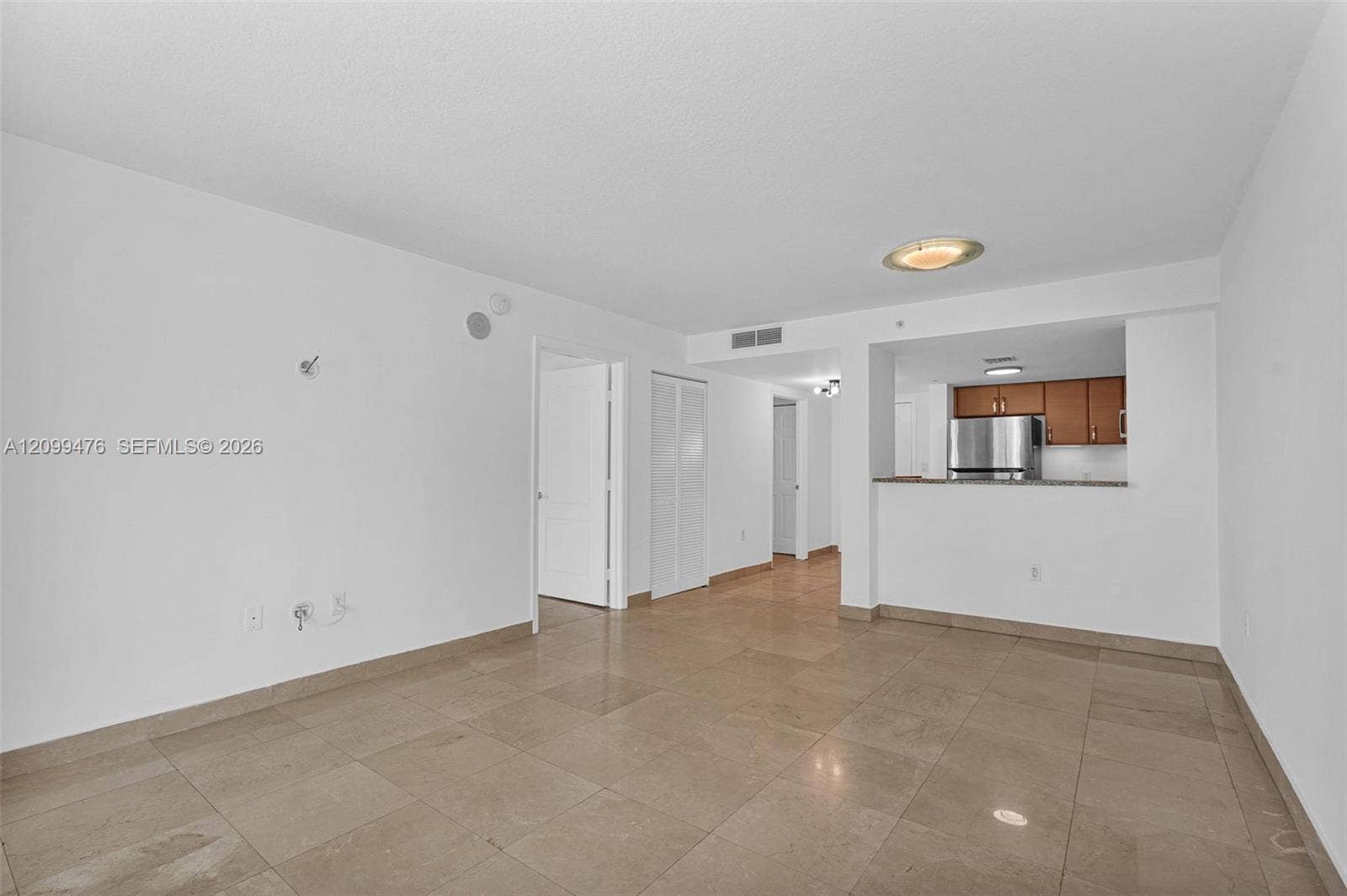 Open-concept room featuring large-format tile flooring, a kitchen pass-through counter, and stainless steel kitchen appliances