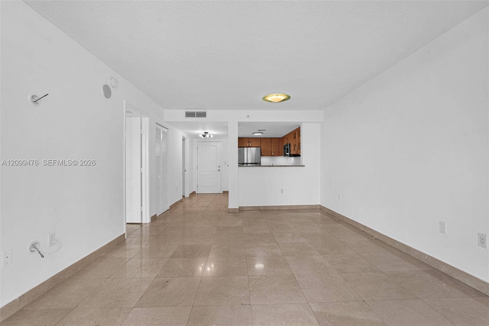 Neutral-toned tile flooring, pass-through kitchen counter, stainless steel refrigerator, and recessed ceiling lighting