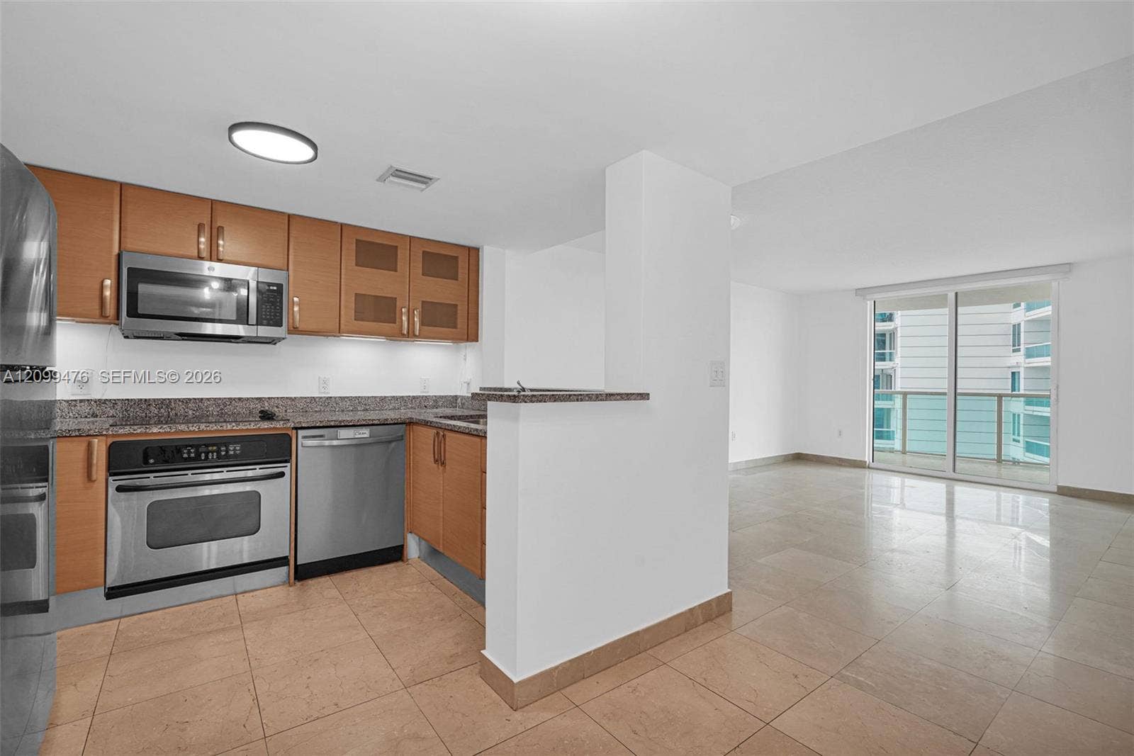 Kitchen featuring natural wood-finish cabinetry, stone-surface countertops, stainless steel appliances, and tile flooring