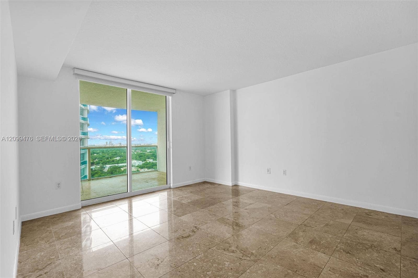 Interior space featuring high-gloss polished stone tile flooring, neutral walls, and a large glass sliding door opening to a private balcony