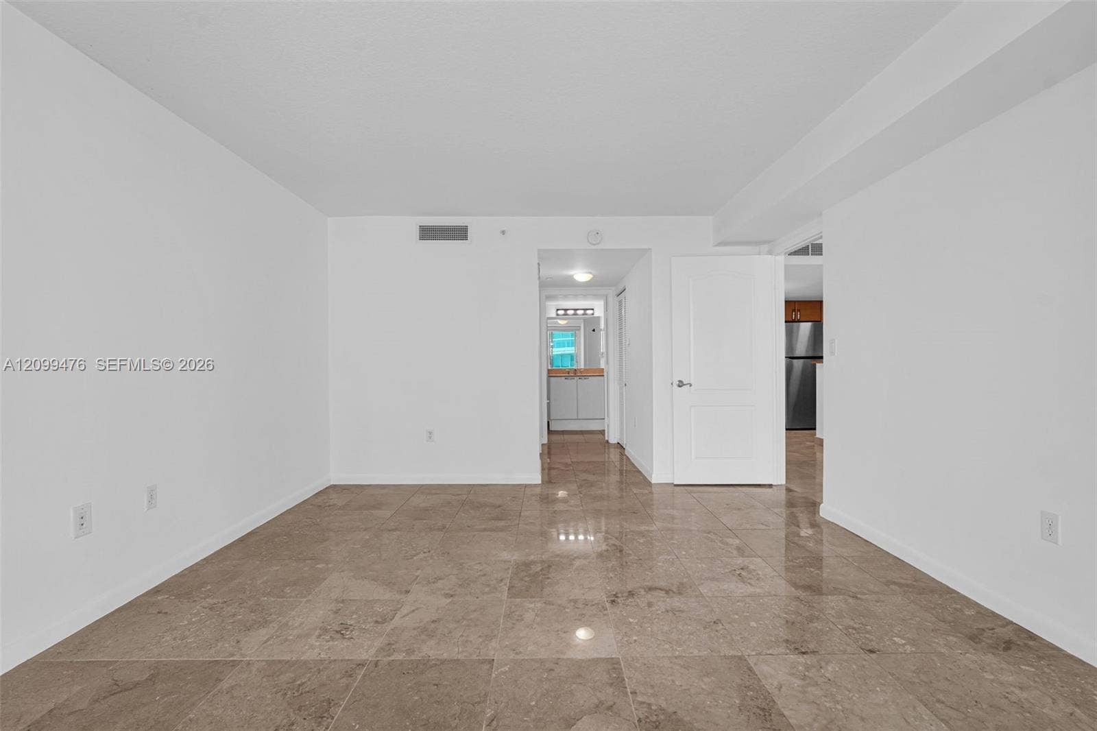 Neutral-toned stone flooring throughout, smooth-finish walls, and a solid-core interior door