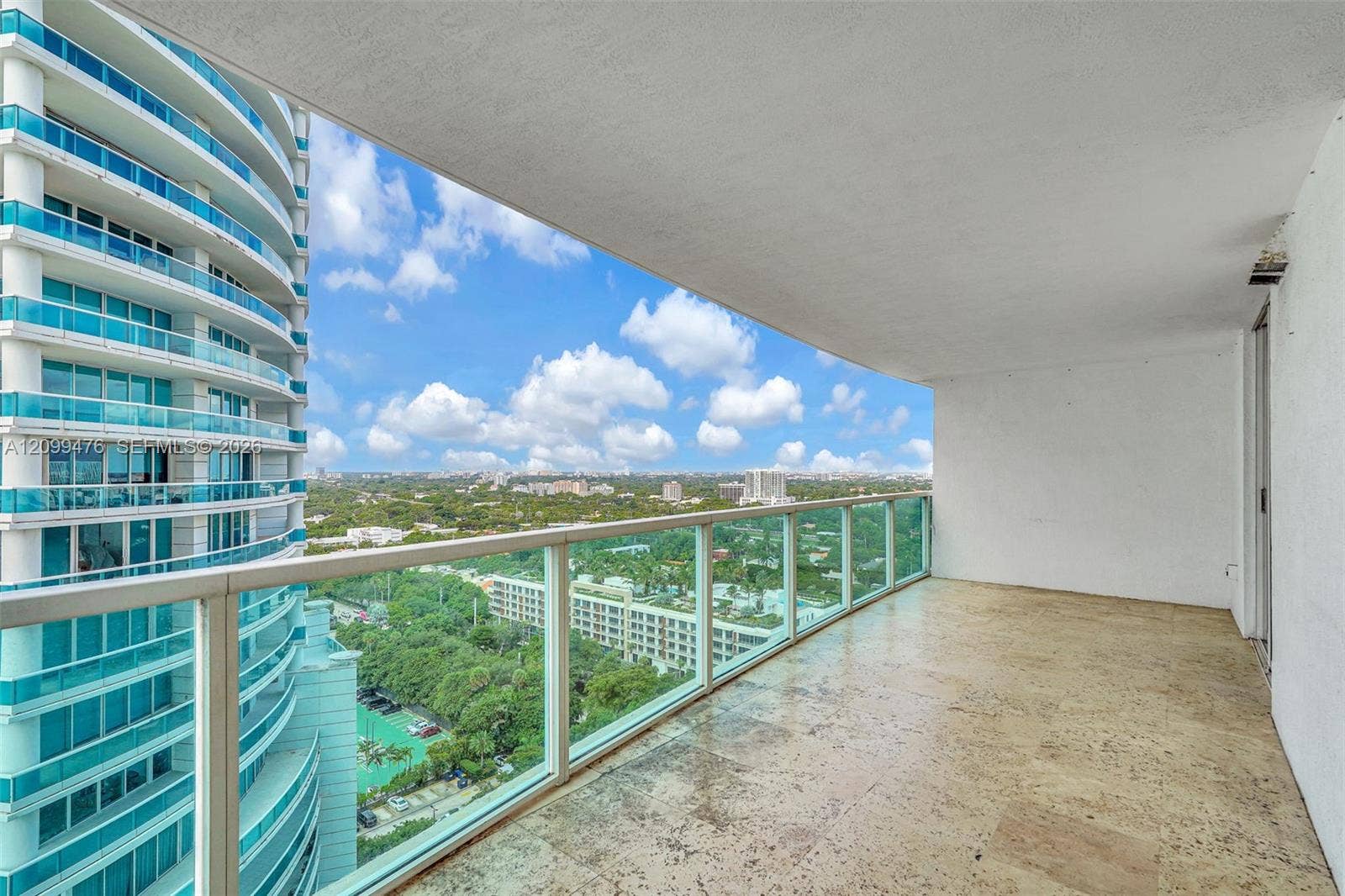 Covered balcony featuring stone flooring and a glass panel railing