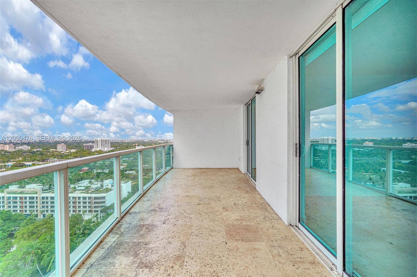 Covered balcony featuring stone tile flooring and glass panel railings