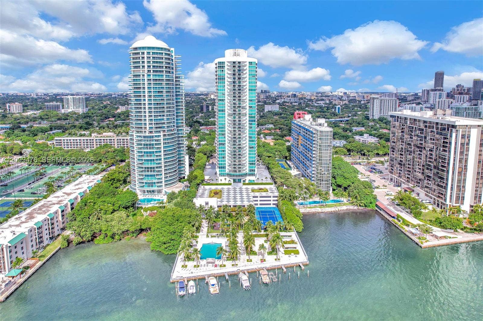 High-rise residential towers featuring waterfront access, private boat slips, an outdoor swimming pool, and dedicated tennis courts