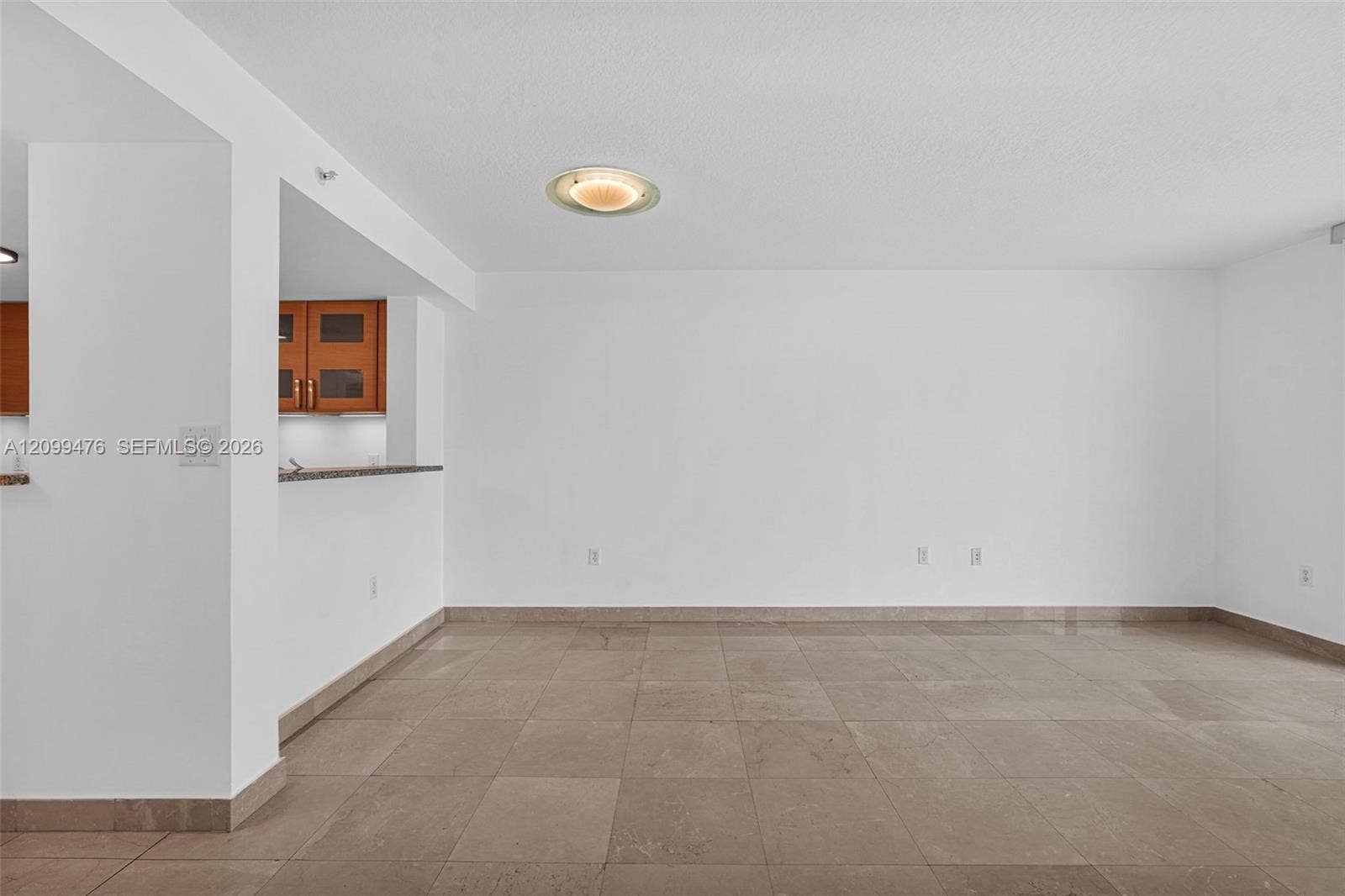 Large-format tile flooring, recessed ceiling lighting, and a breakfast bar with stone-finish countertop