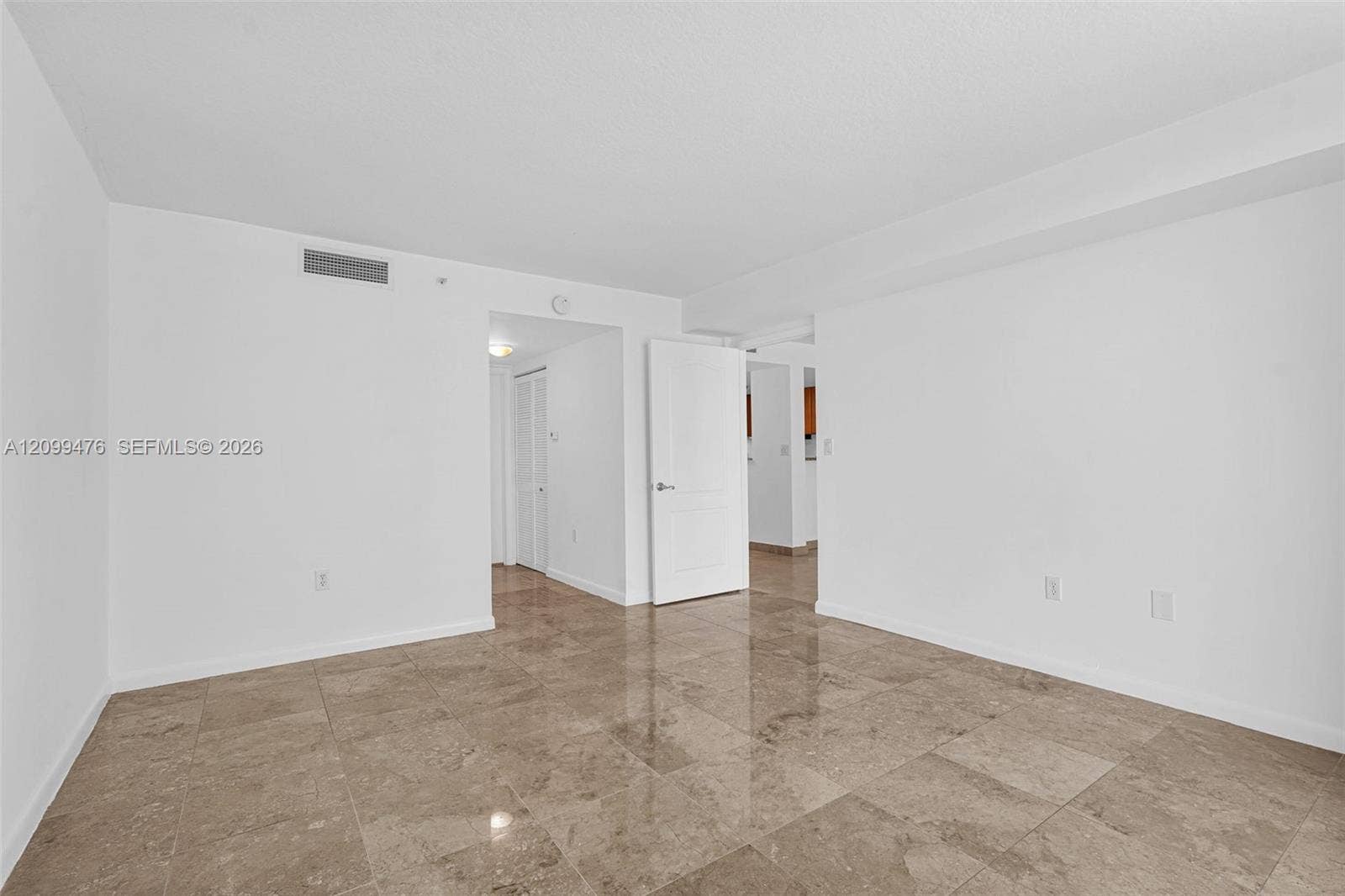 Neutral interior space featuring polished stone flooring, solid-core interior doors, and clean, white-painted wall finishes