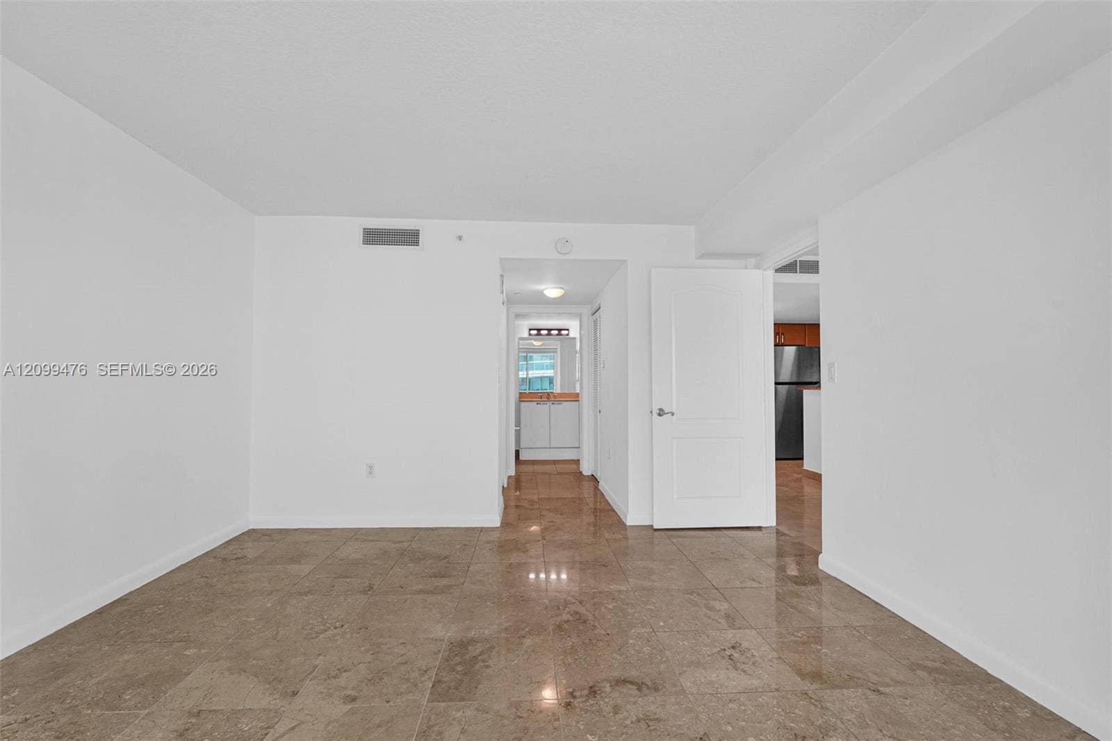 Open-concept interior featuring large-format tile flooring, neutral wall finishes, and a solid-core panel door