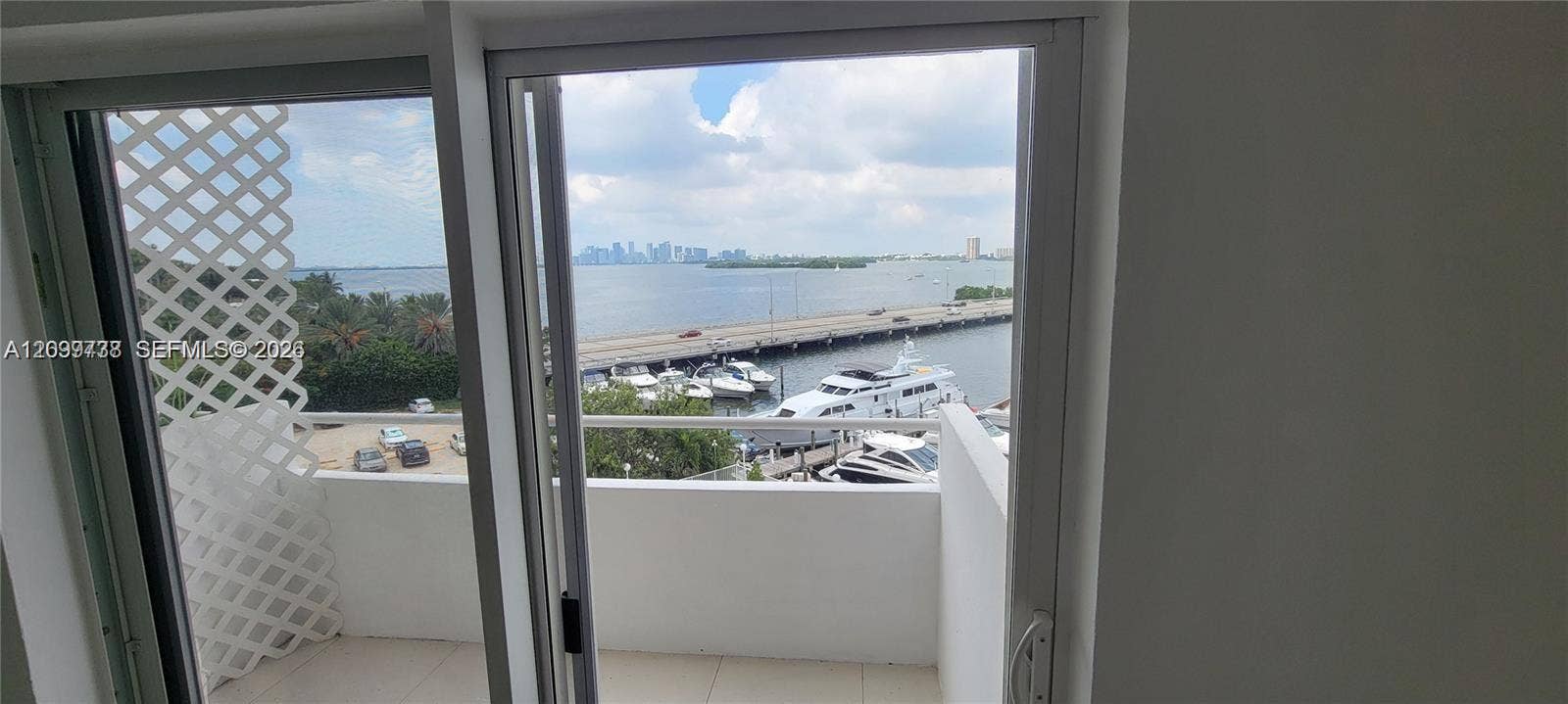 7904 West Drive, #514, North Bay Village, North Bay Village, FL 33141 Private balcony featuring tiled flooring, solid wall railings, and a lattice privacy screen, showcasing water, marina, and city skyline scenery