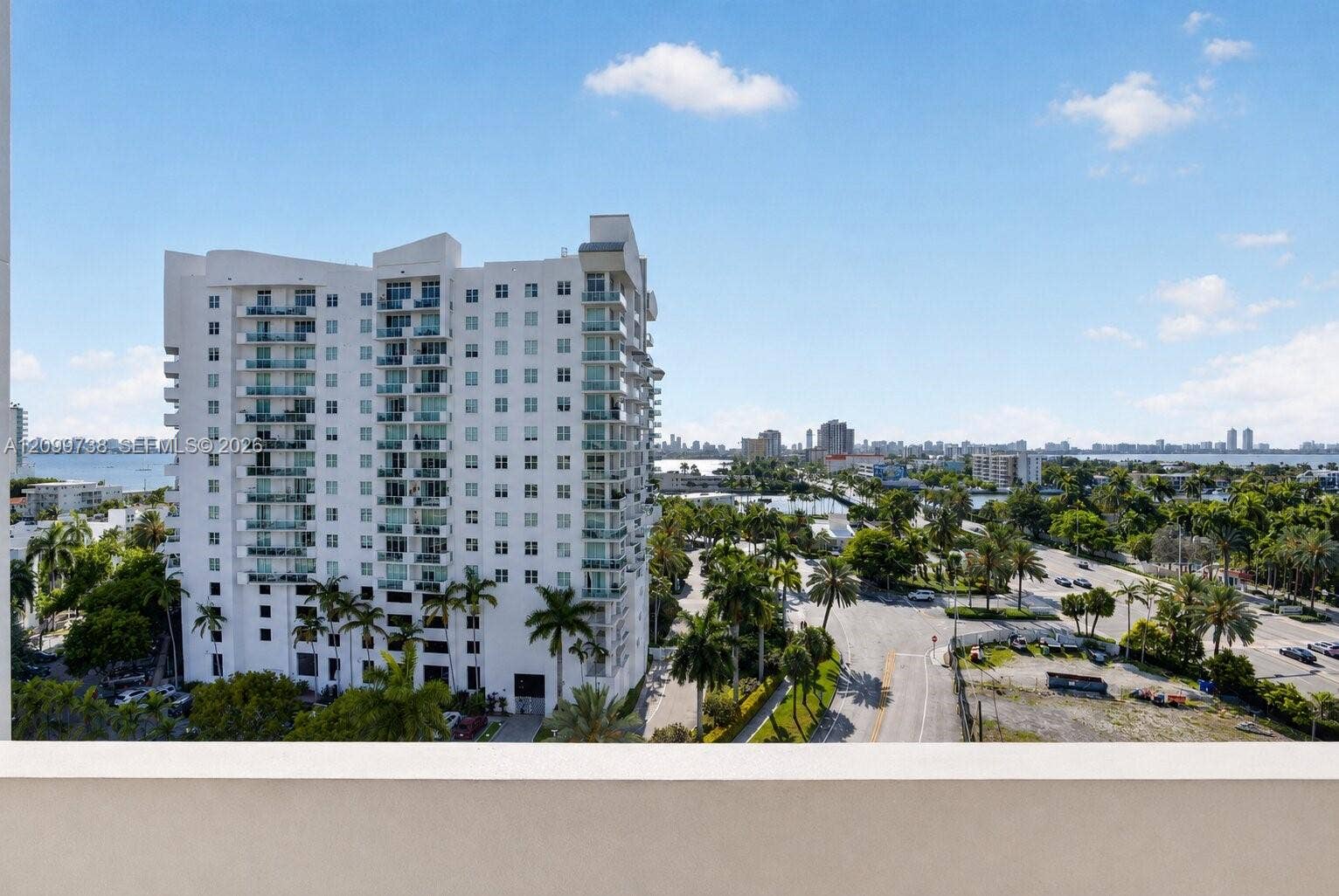 7904 West Drive, #514, North Bay Village, North Bay Village, FL 33141 High-rise balcony featuring a solid masonry railing and a perspective of the coastal cityscape, including surrounding palm trees, local thoroughfares, and nearby water