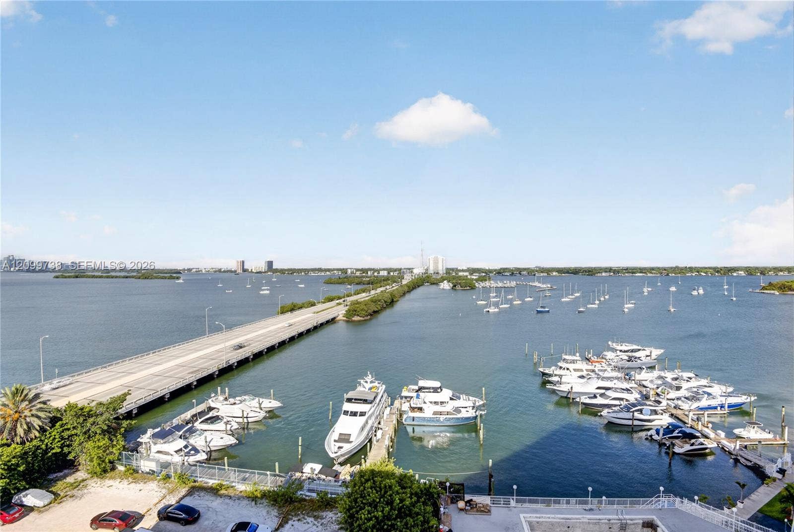 Waterfront setting featuring a private marina with multiple deep-water slips, paved causeway access, and panoramic coastal horizon