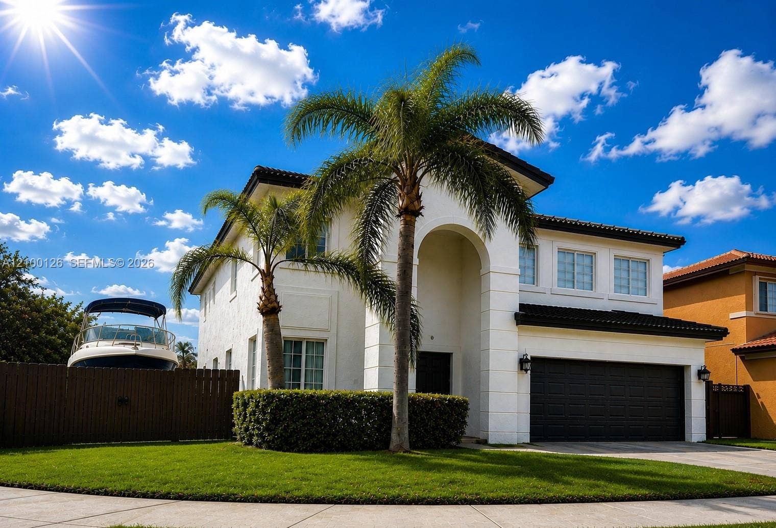 Two-story residence featuring a stucco exterior, arched covered entryway, multi-paned windows, attached two-car garage, and manicured landscaping