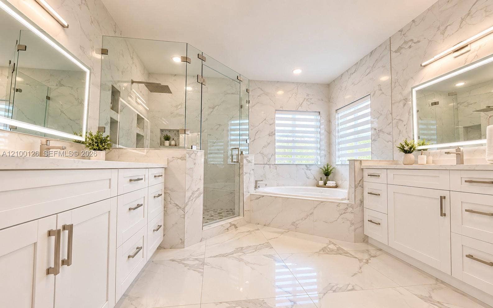 Dual white vanities with integrated sinks, glass-enclosed shower, built-in soaking tub, and floor-to-ceiling stone-patterned tile throughout