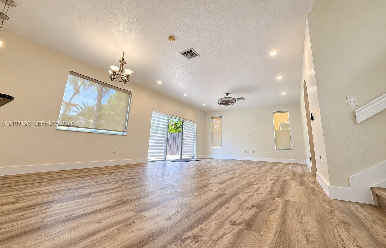 Open-concept interior featuring wood-finish flooring, recessed lighting, a ceiling fan, and sliding glass doors with roller shades
