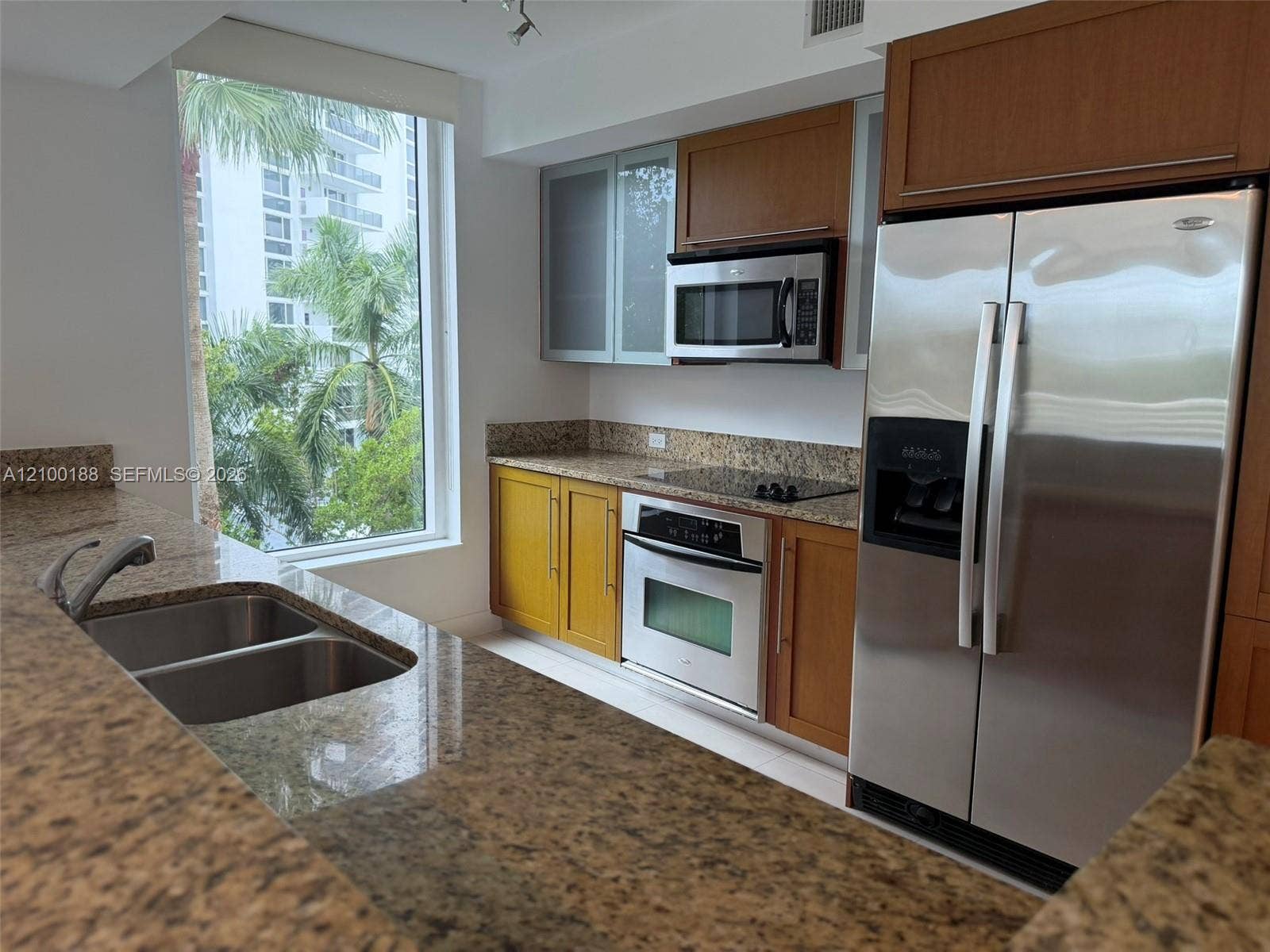 2821 N Ocean Boulevard, #305S, Fort Lauderdale, Fort Lauderdale, FL 33308 Kitchen featuring stone countertops, stainless steel appliances, wood cabinetry, dual-basin sink with pull-down faucet, and floor-to-ceiling window
