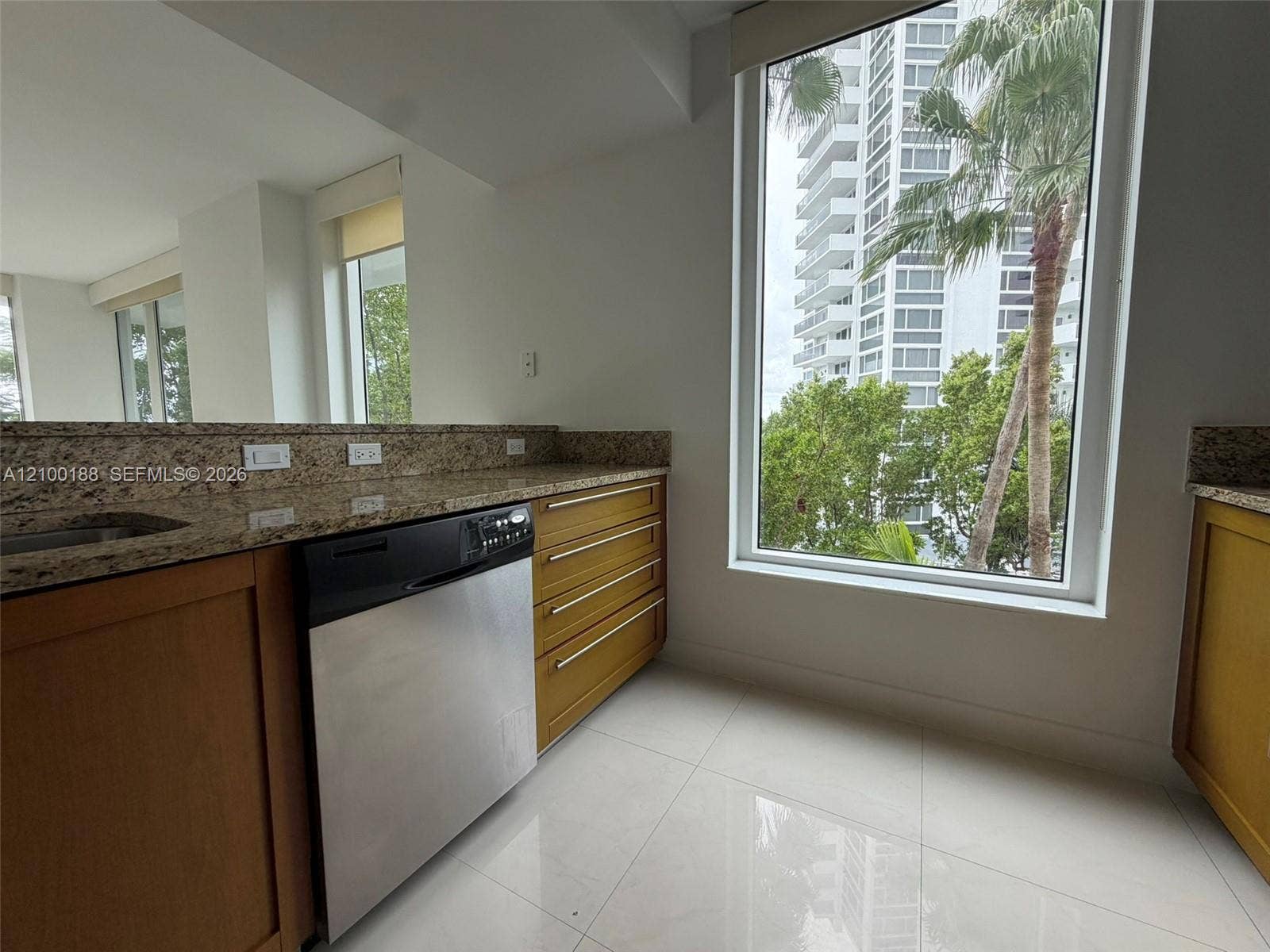 2821 N Ocean Boulevard, #305S, Fort Lauderdale, Fort Lauderdale, FL 33308 Kitchen featuring natural stone countertops, warm-toned wood cabinetry, stainless steel dishwasher, floor-to-ceiling windows, and polished tile flooring