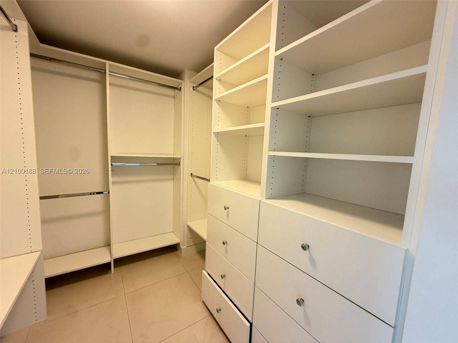2821 N Ocean Boulevard, #305S, Fort Lauderdale, Fort Lauderdale, FL 33308 Custom closet featuring white built-in cabinetry, floor-to-ceiling shelving, integrated hanging rods, and large-format tile flooring