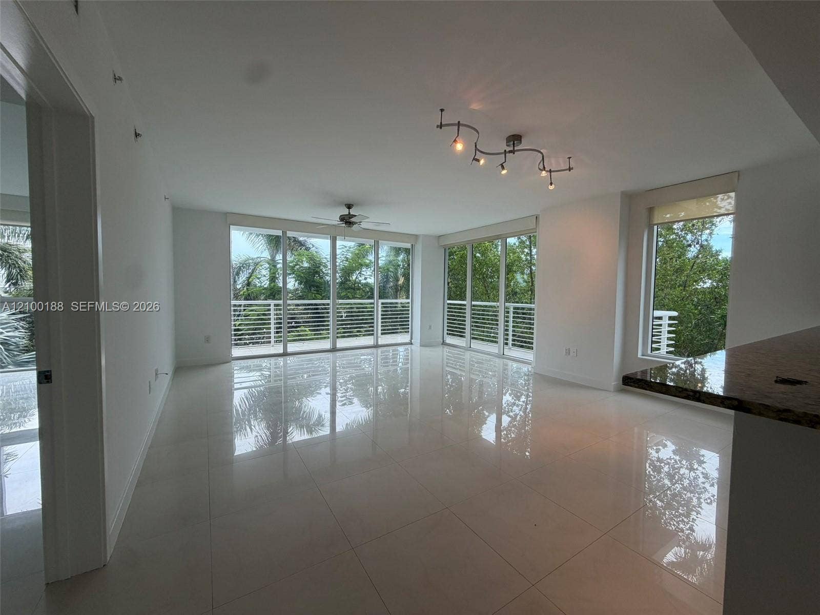 2821 N Ocean Boulevard, #305S, Fort Lauderdale, Fort Lauderdale, FL 33308 Open-concept interior featuring large-format tile flooring, expansive floor-to-ceiling windows, polished stone kitchen peninsula, contemporary multi-light fixture, and ceiling fan