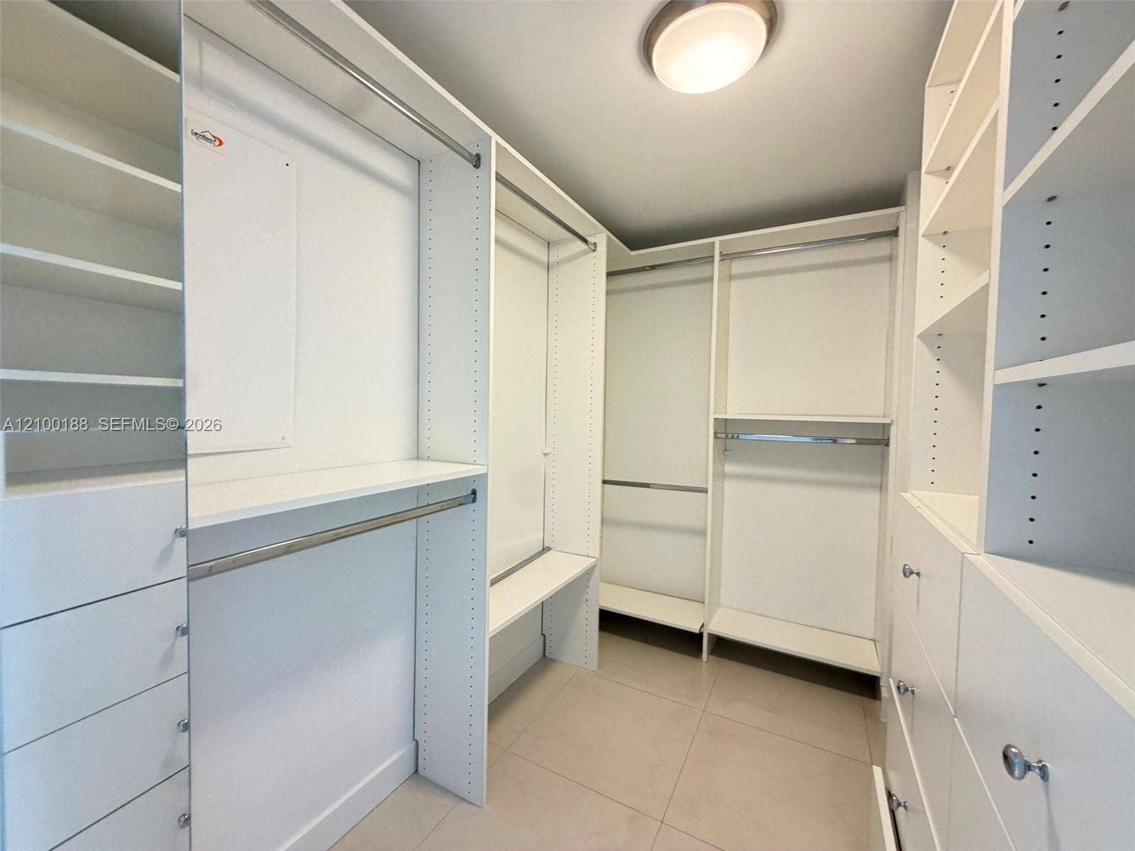 2821 N Ocean Boulevard, #305S, Fort Lauderdale, Fort Lauderdale, FL 33308 Walk-in closet featuring white custom built-in shelving, multiple hanging rods, integrated drawer storage, and tile flooring